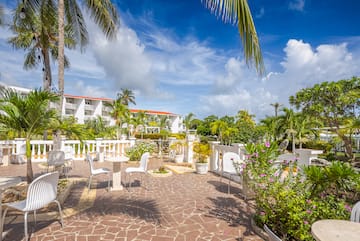 a patio with white chairs and trees