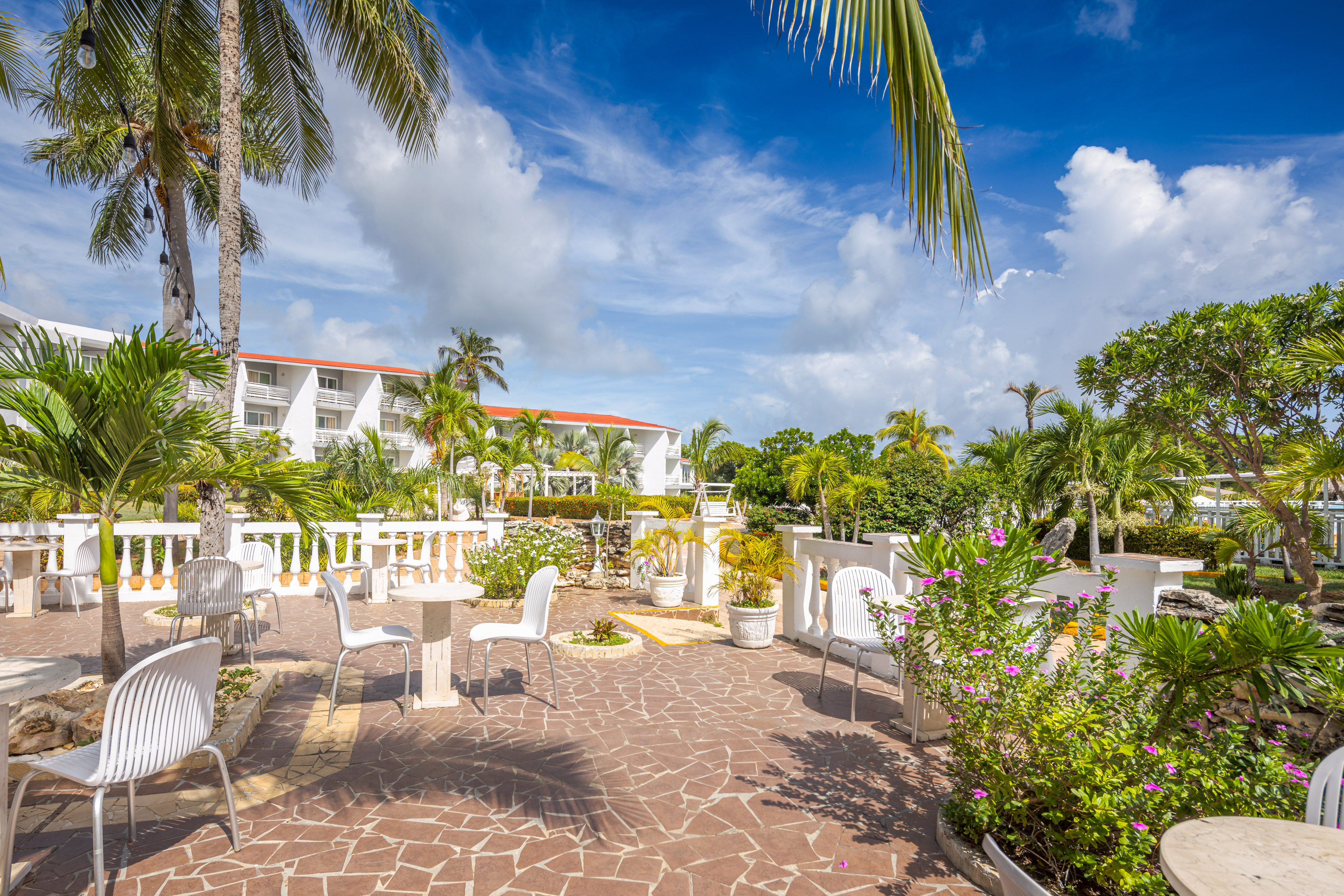 a patio with white chairs and trees