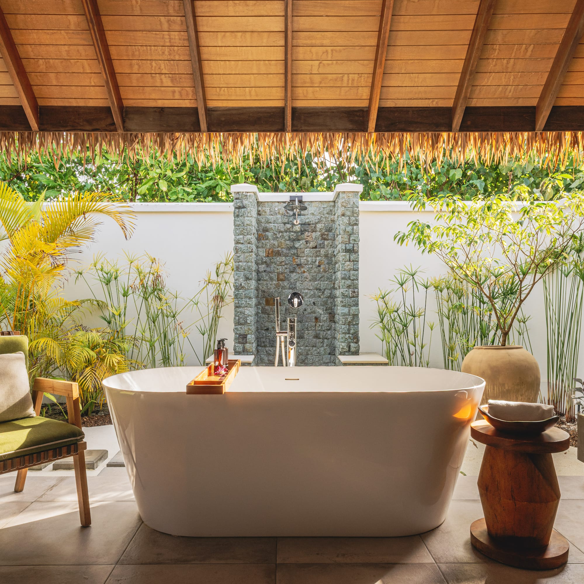 a bathtub outside with a shower and plants