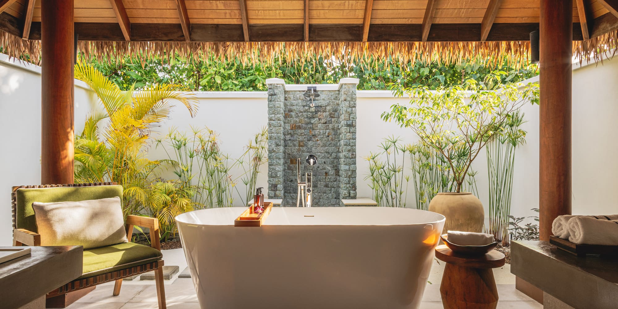 a bathtub outside with a shower and plants
