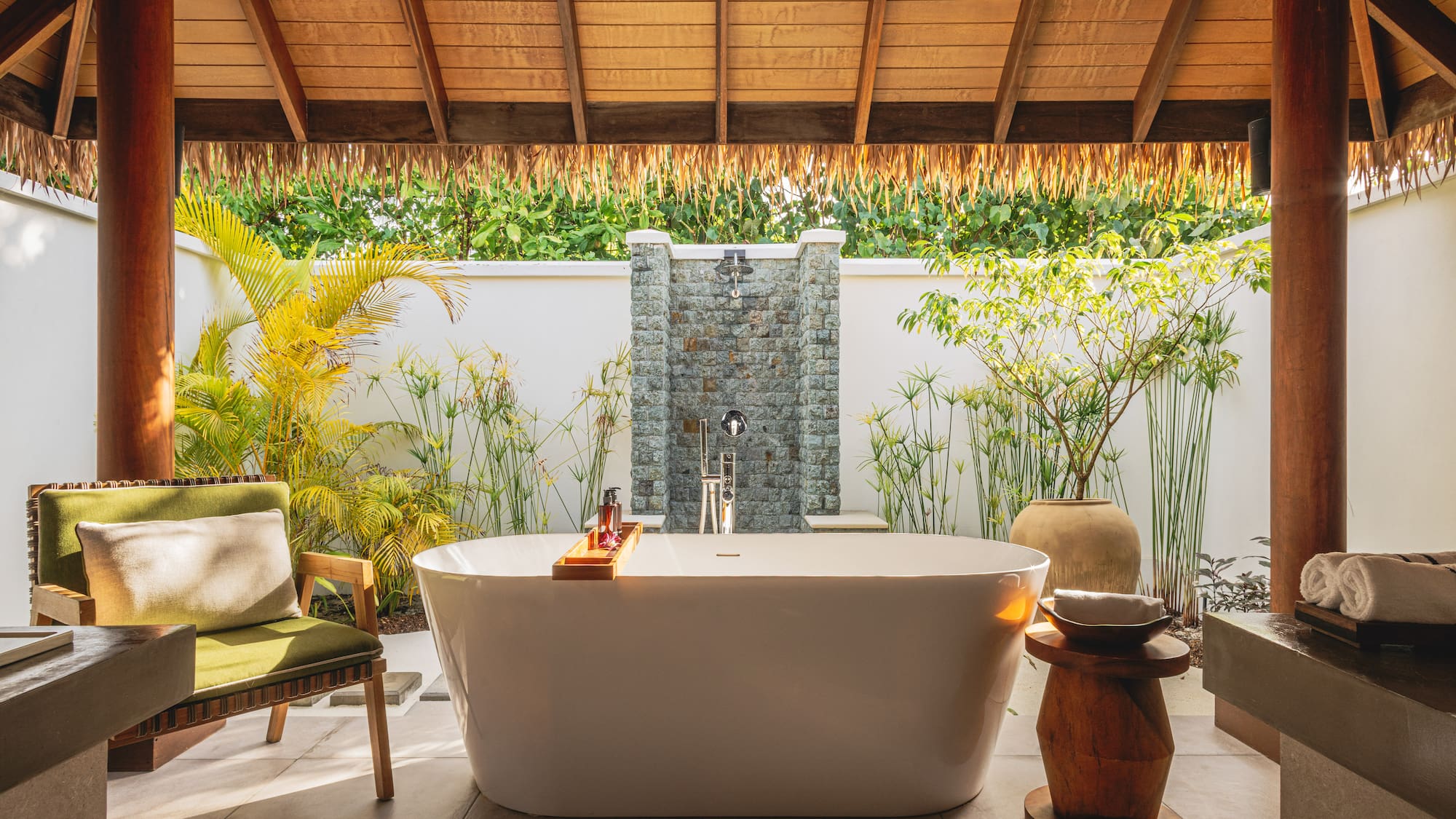 a bathtub outside with a shower and plants