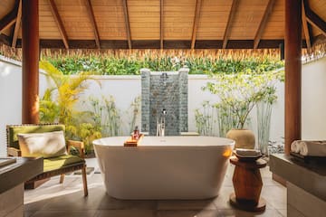 a bathtub outside with a shower and plants