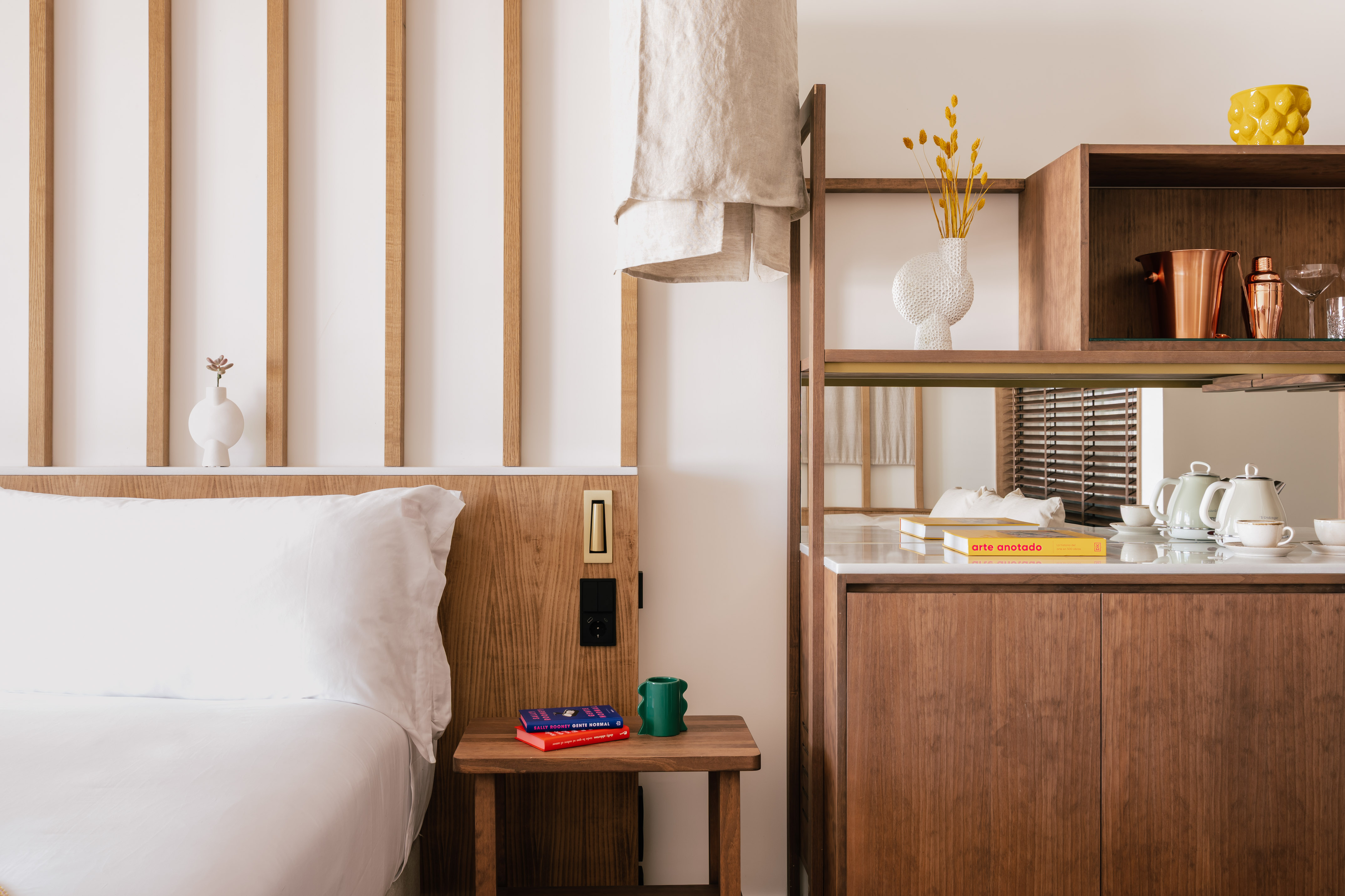 Modern bedroom with wooden headboard, white bed, and integrated minibar.