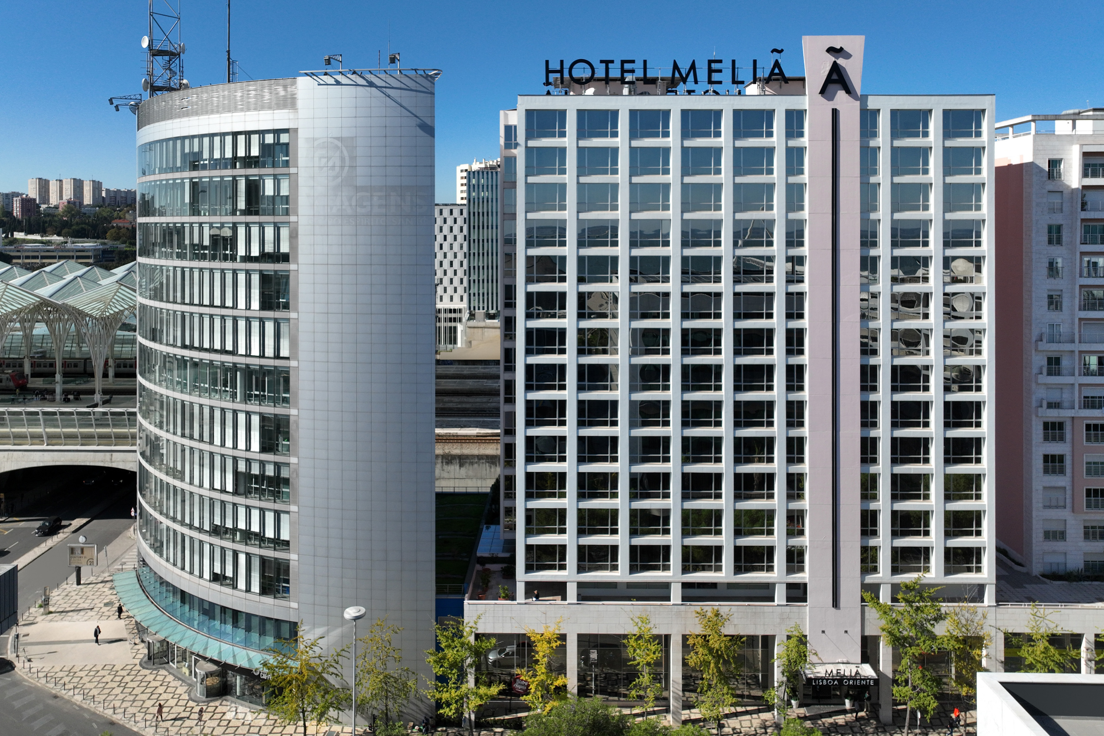 Hotel Meliã Lisboa Oriente and adjacent modern curved building in city.