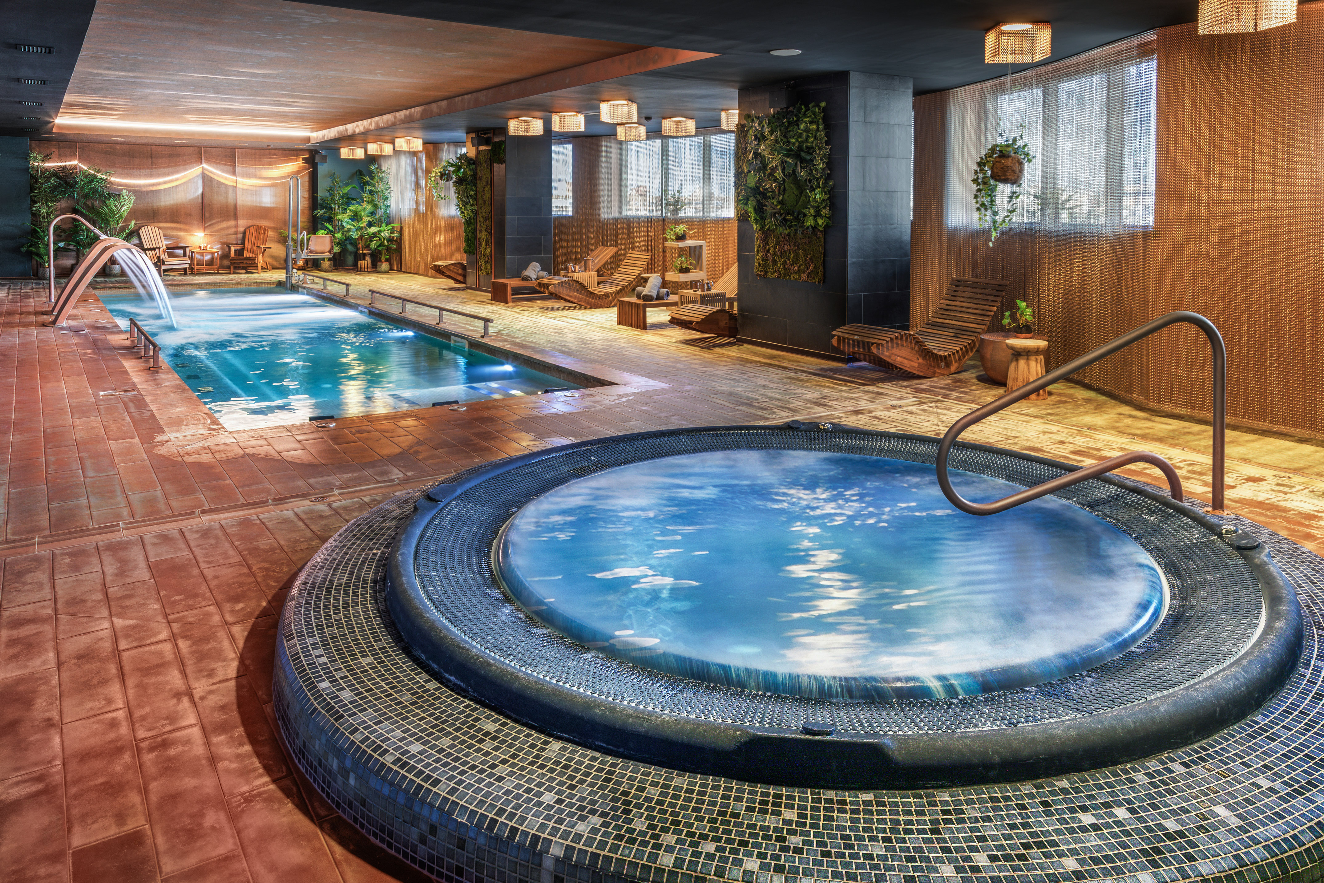 Luxury indoor spa with swimming pool, hot tub, and modern lounge chairs.