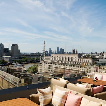 a rooftop bar with a view of a city and a river