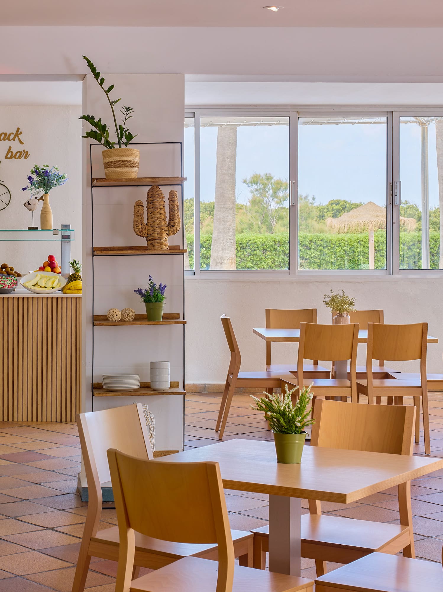 Snack bar buffet with fresh fruit, dining tables, and outdoor pool view.