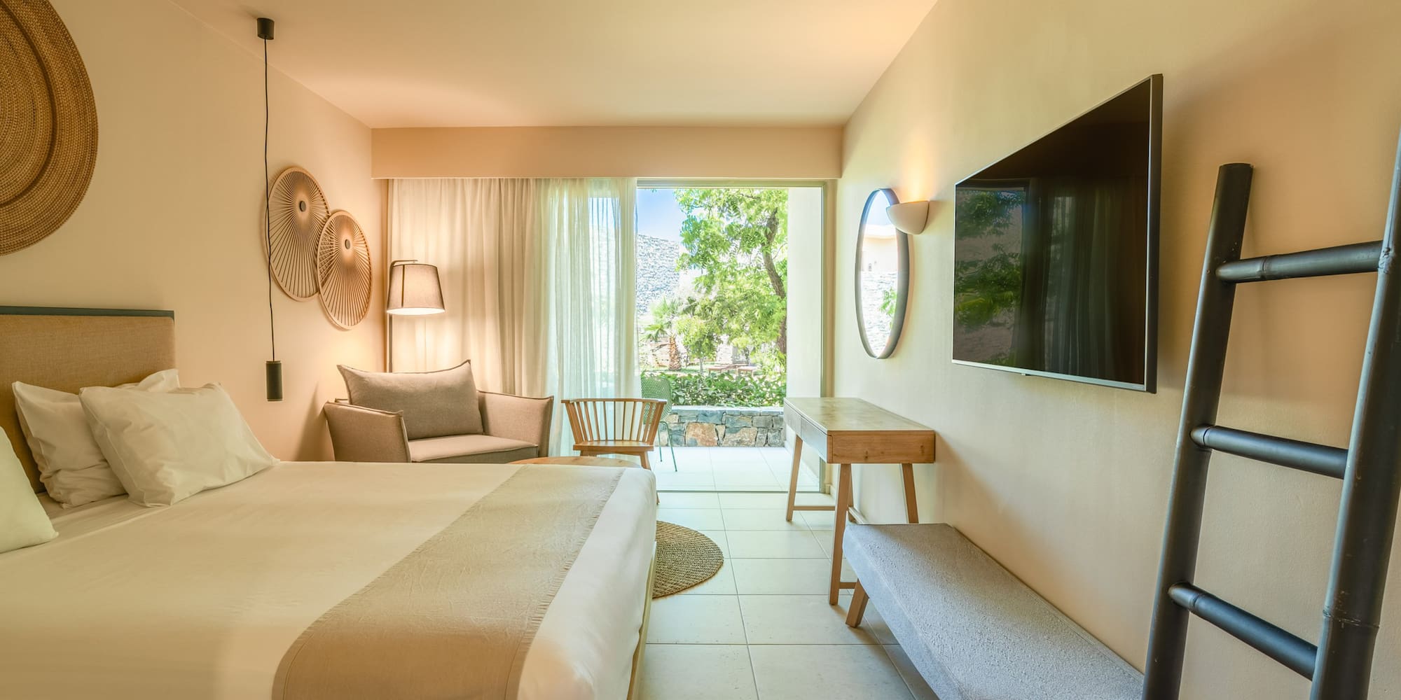 Stylish hotel bedroom with private balcony, garden view, and modern decor.