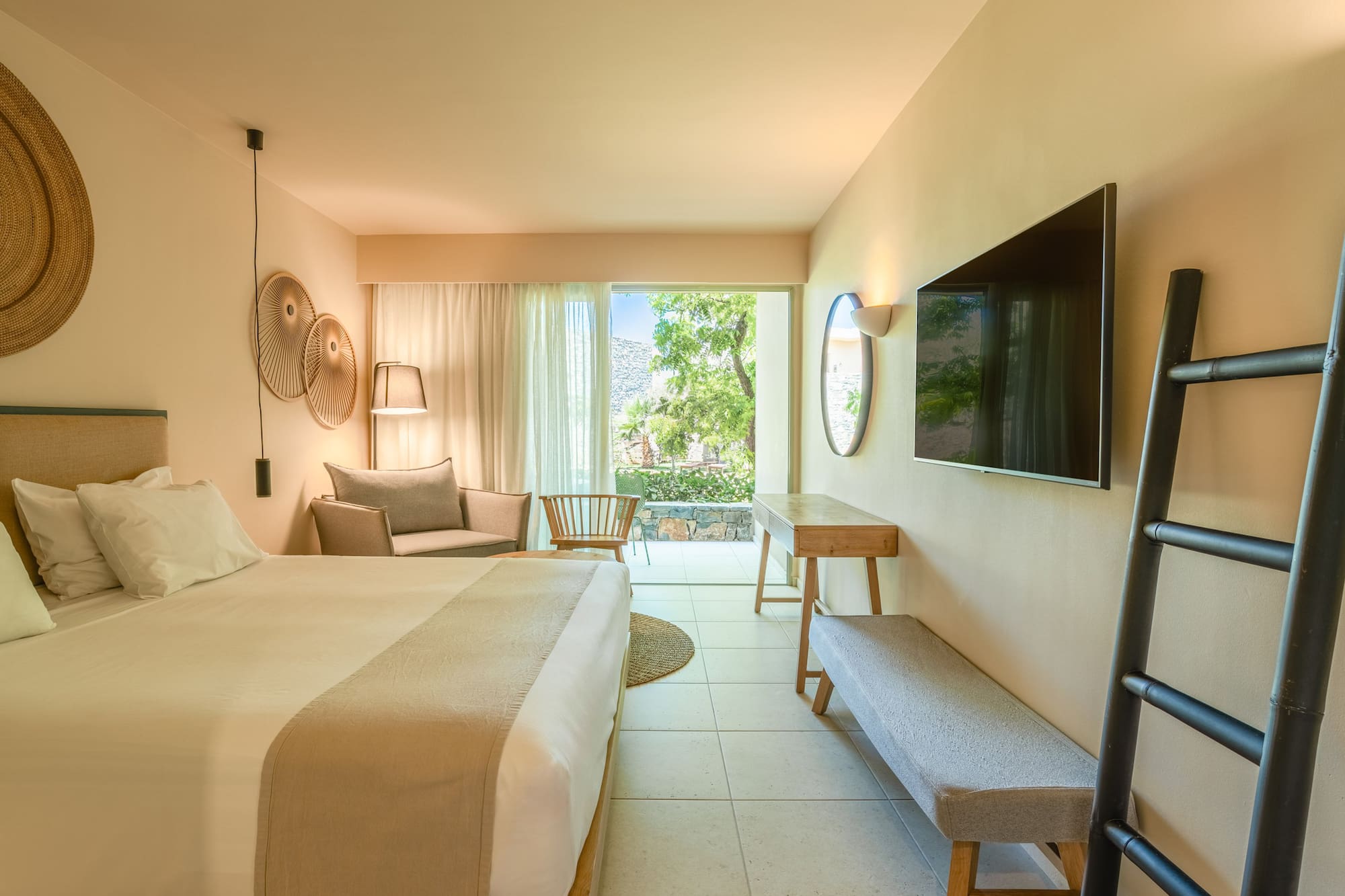 Stylish hotel bedroom with private balcony, garden view, and modern decor.