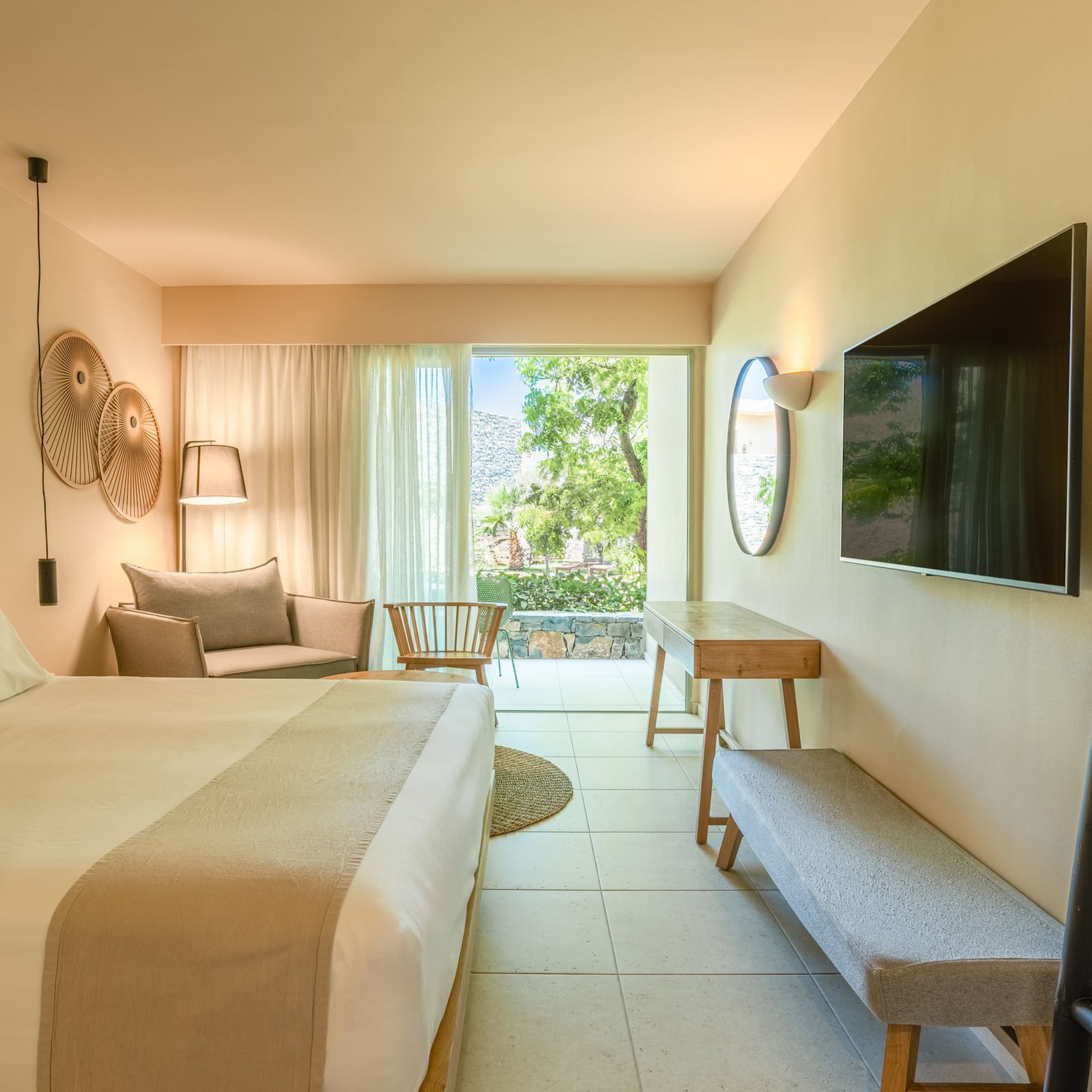 Stylish hotel bedroom with private balcony, garden view, and modern decor.
