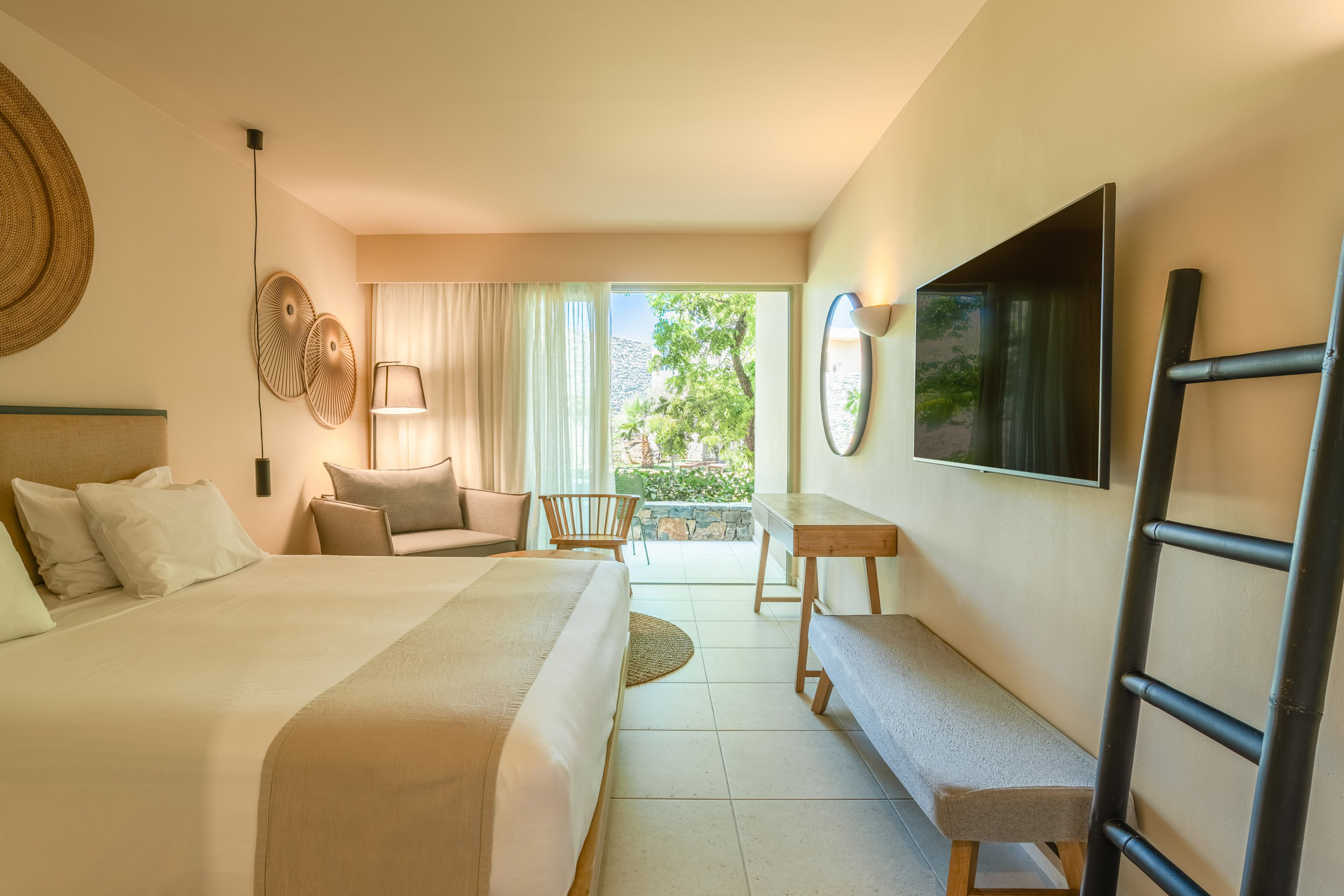 Stylish hotel bedroom with private balcony, garden view, and modern decor.