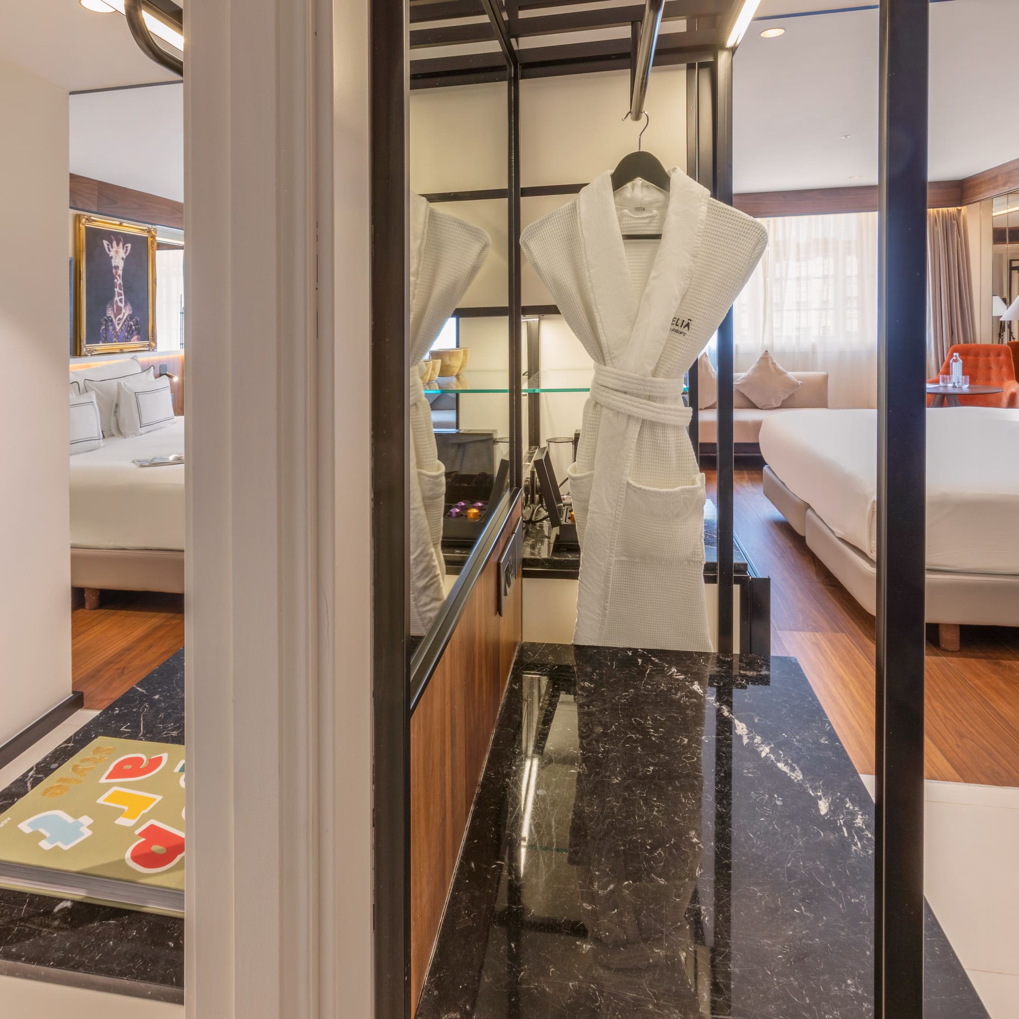 Modern hotel suite with bed, white bathrobe, and dark marble counter.