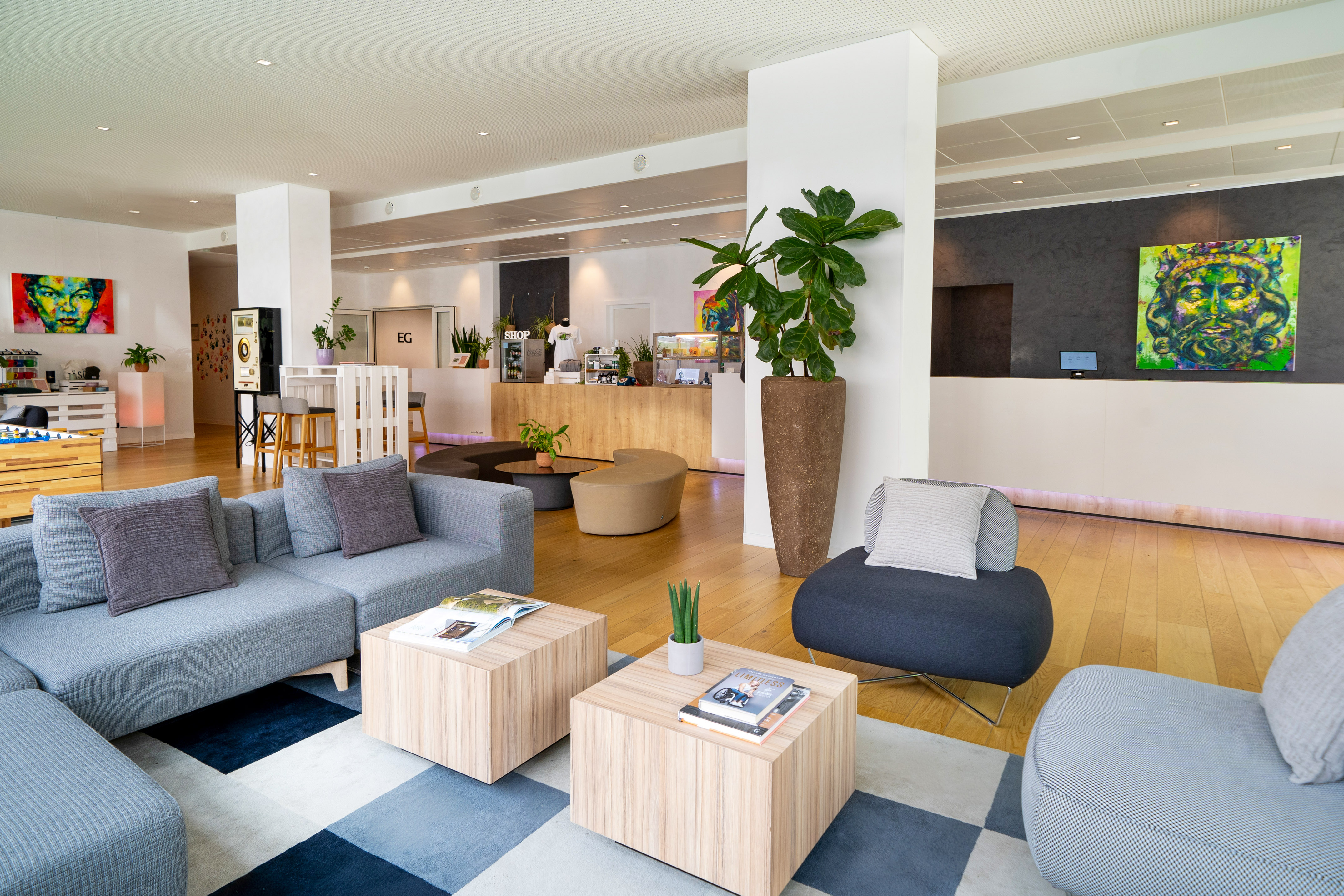 Modern hotel lobby lounge with comfortable seating, reception, and colorful art.