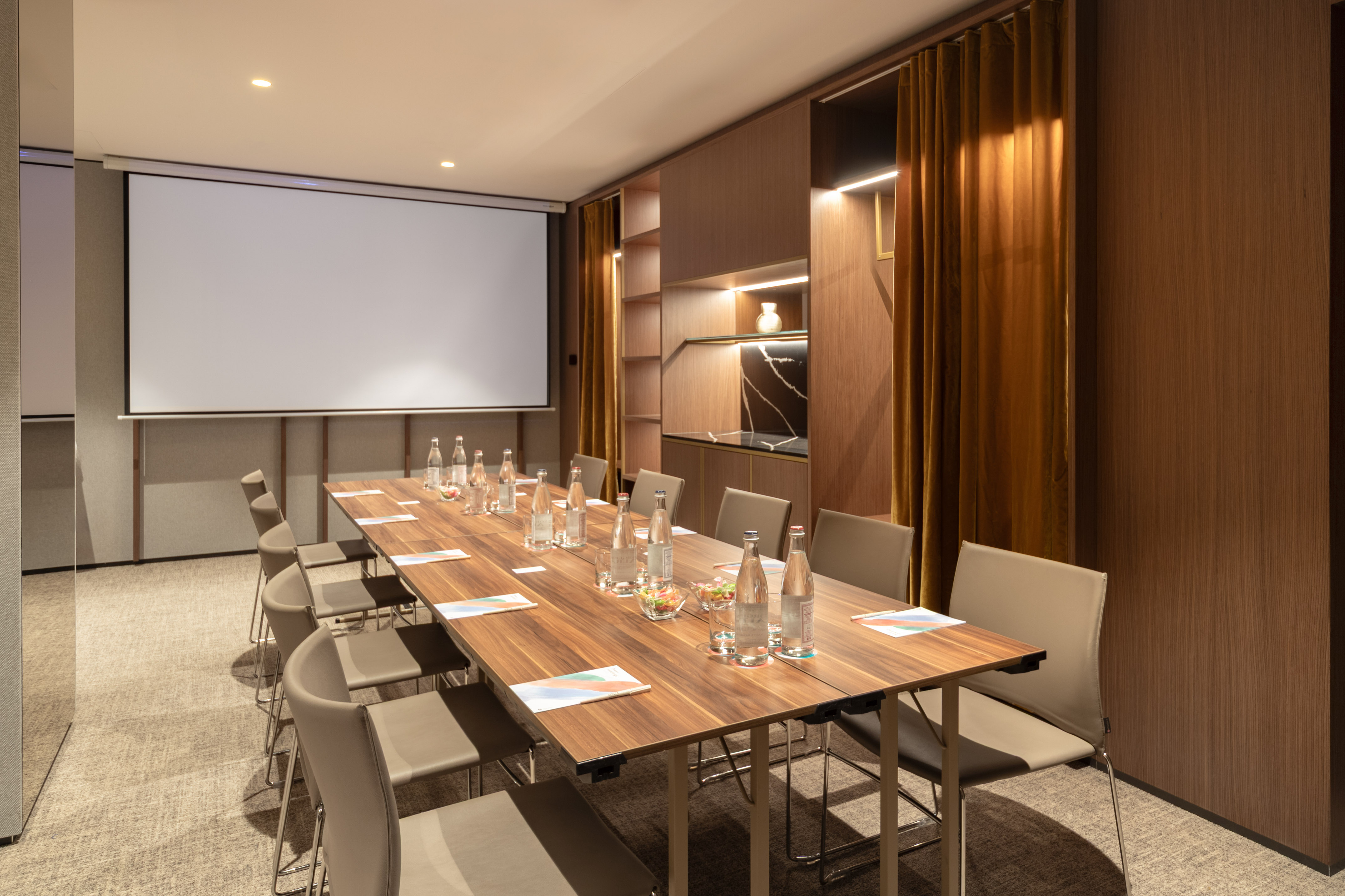 Modern conference room, long table, chairs, and projection screen.