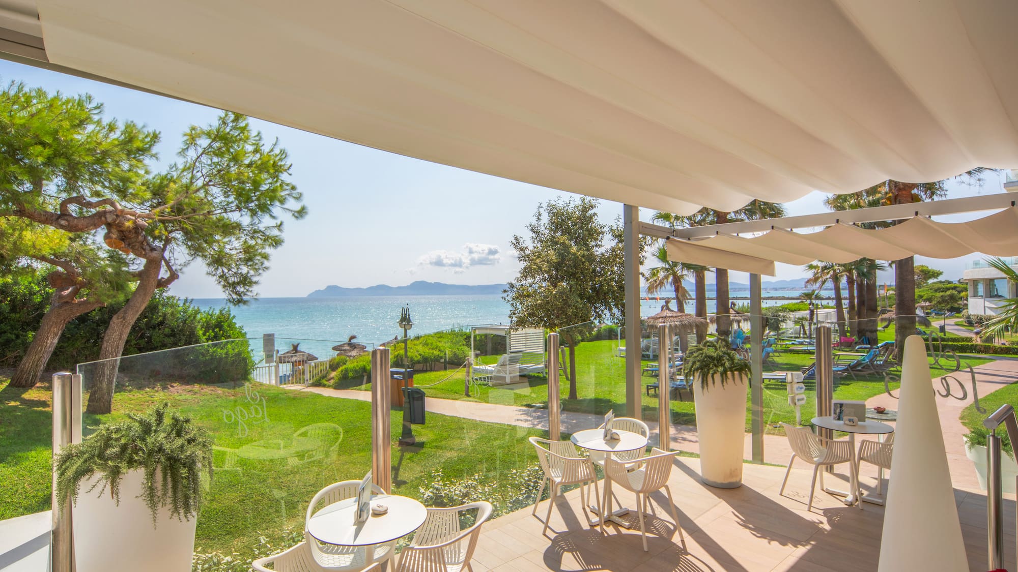 a patio with chairs and tables and a view of the ocean