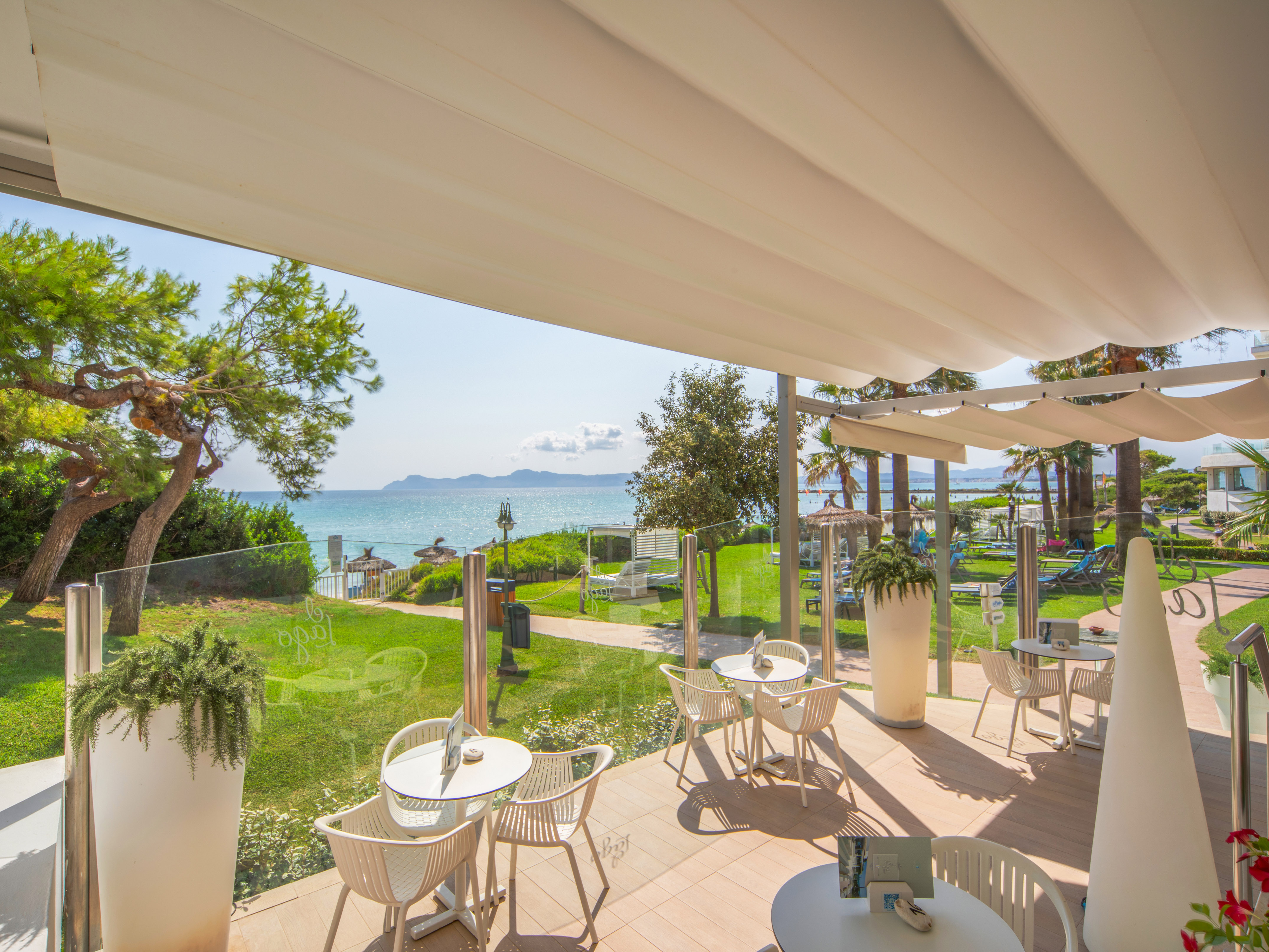 a patio with chairs and tables and a view of the ocean