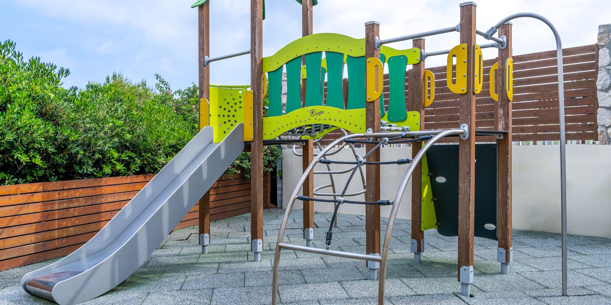 Modern outdoor playground with slide, climbing ropes, and colorful structures.