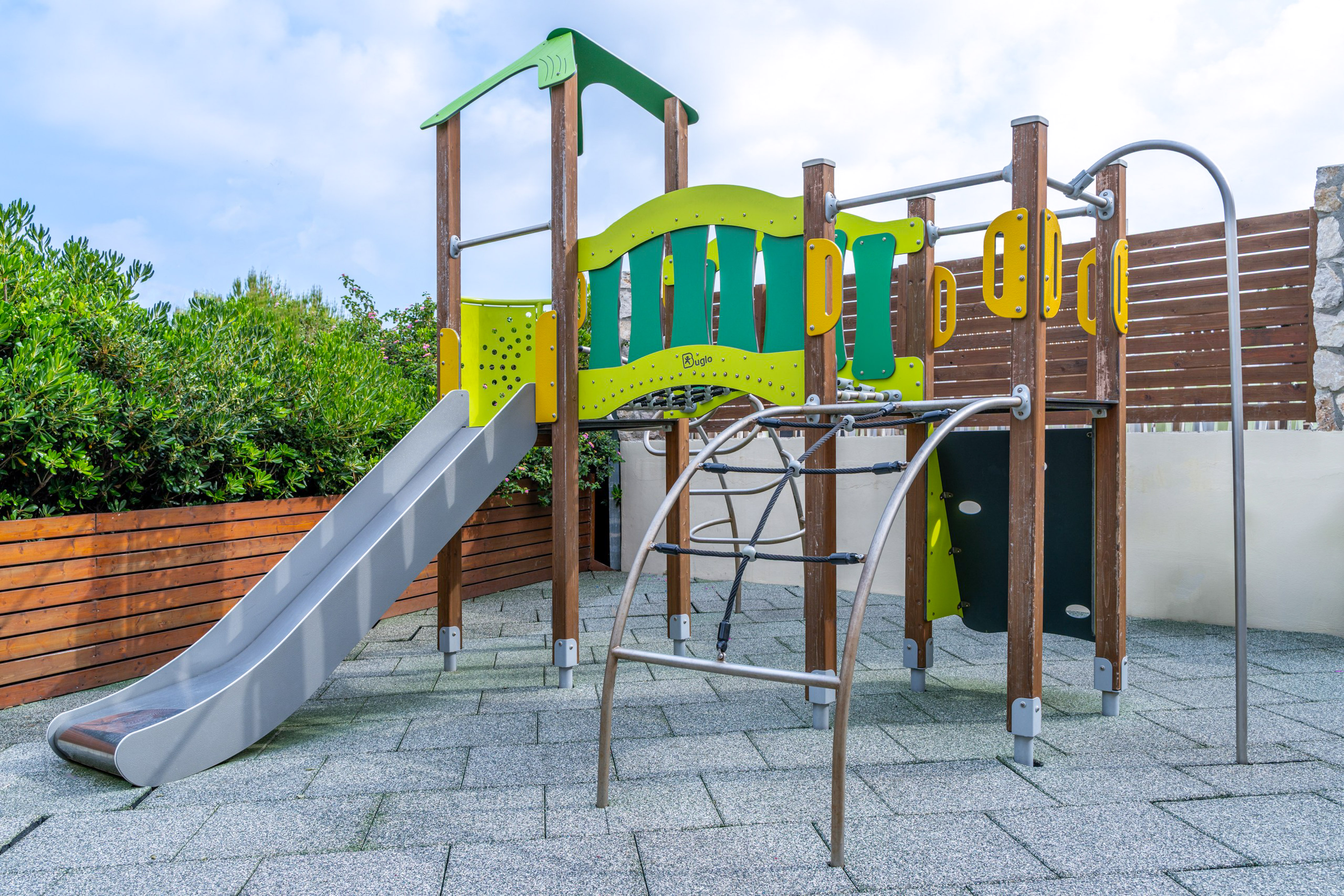Modern outdoor playground with slide, climbing ropes, and colorful structures.