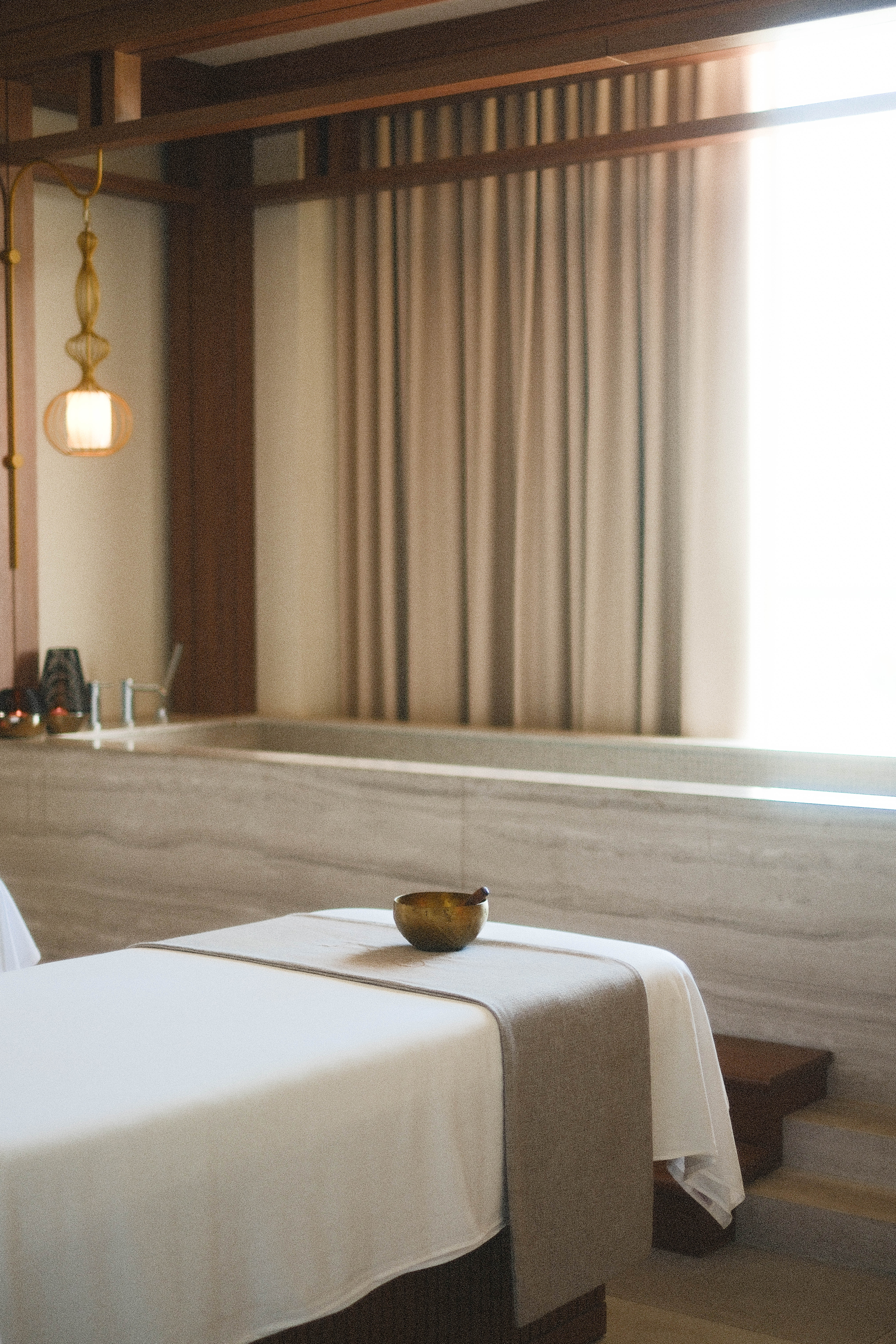 Relaxing spa massage room with table, singing bowl, and soft warm light.