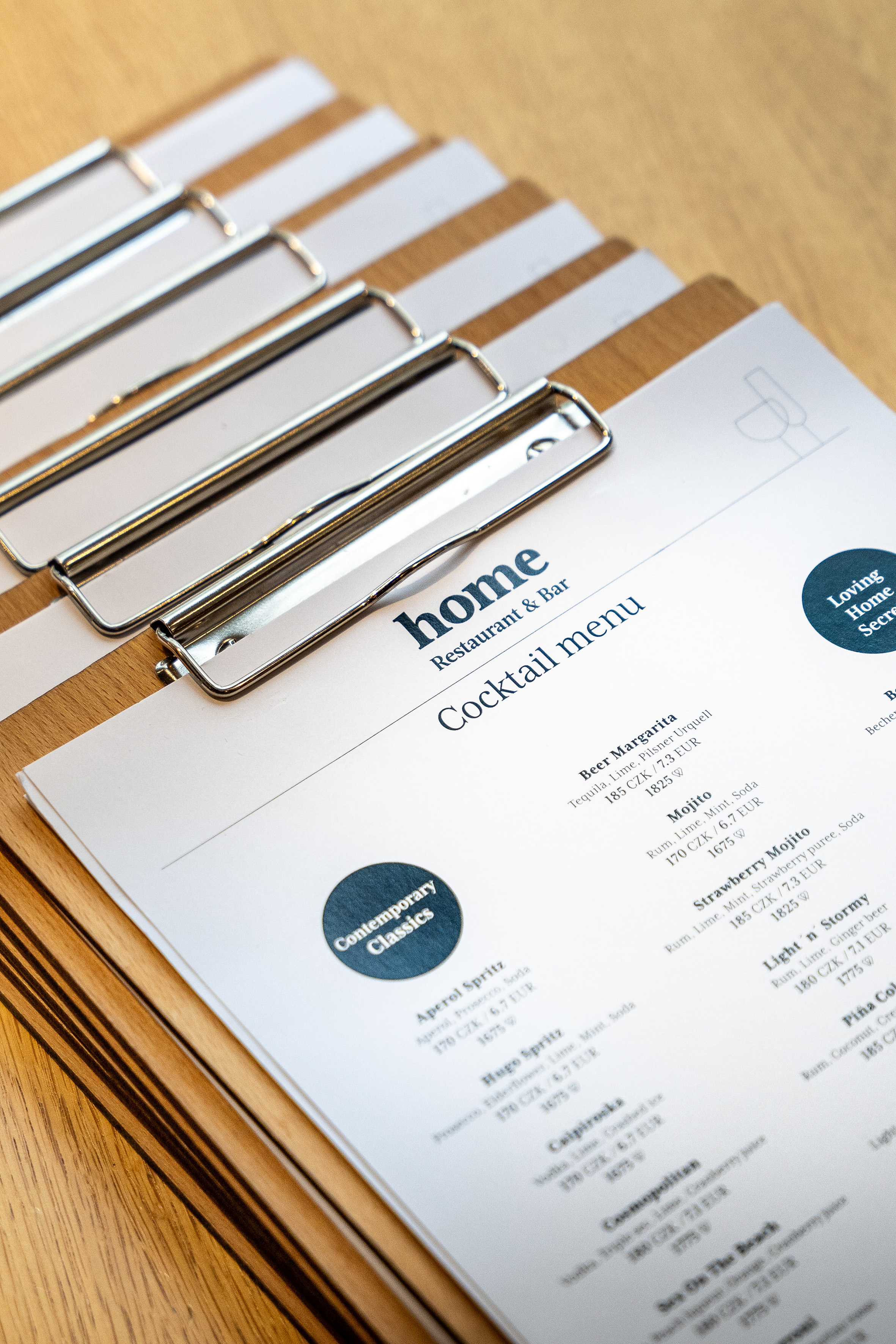 Home Restaurant & Bar cocktail menu with prices on a wooden clipboard.