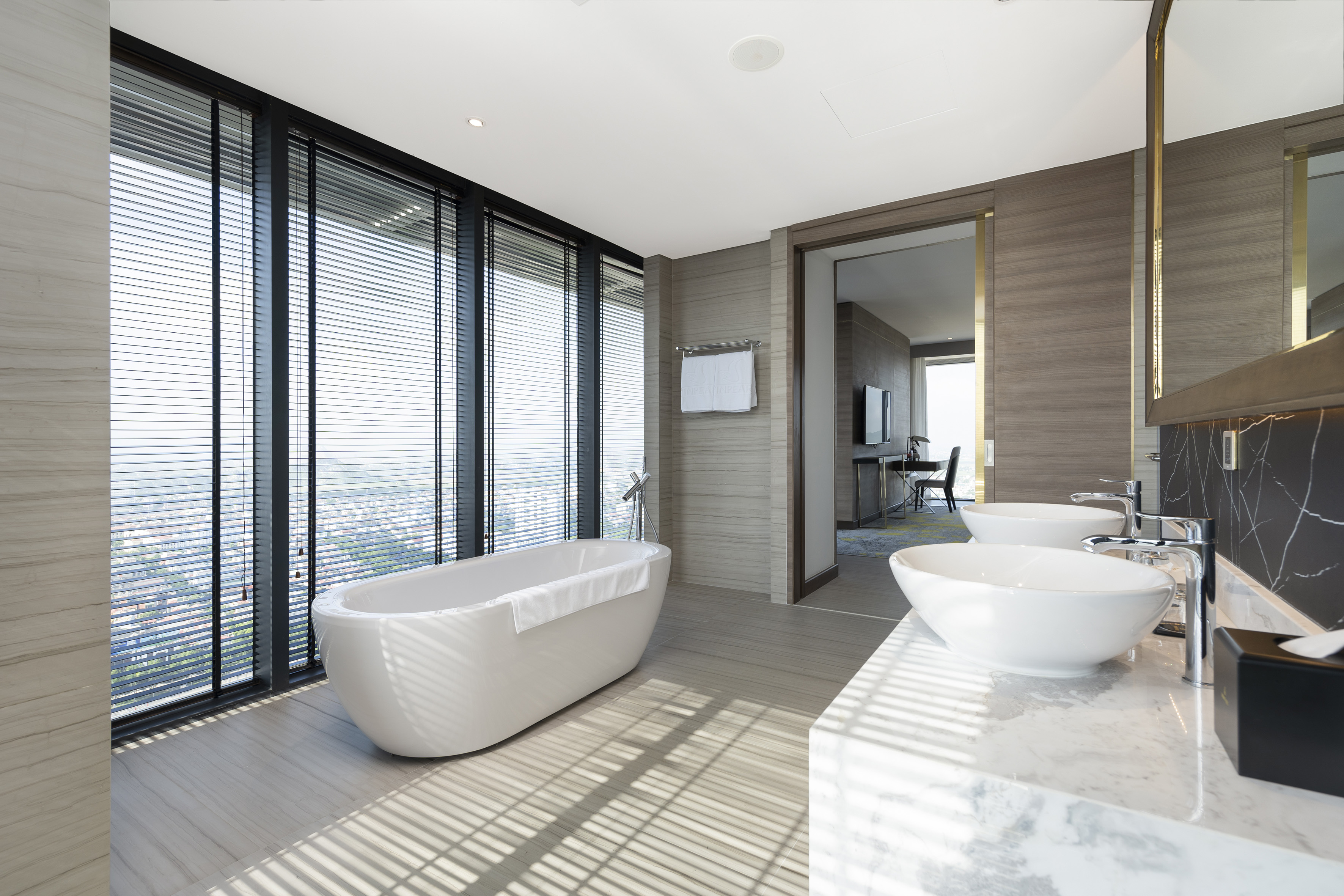 Modern luxury bathroom with freestanding tub, dual vessel sinks, city view.