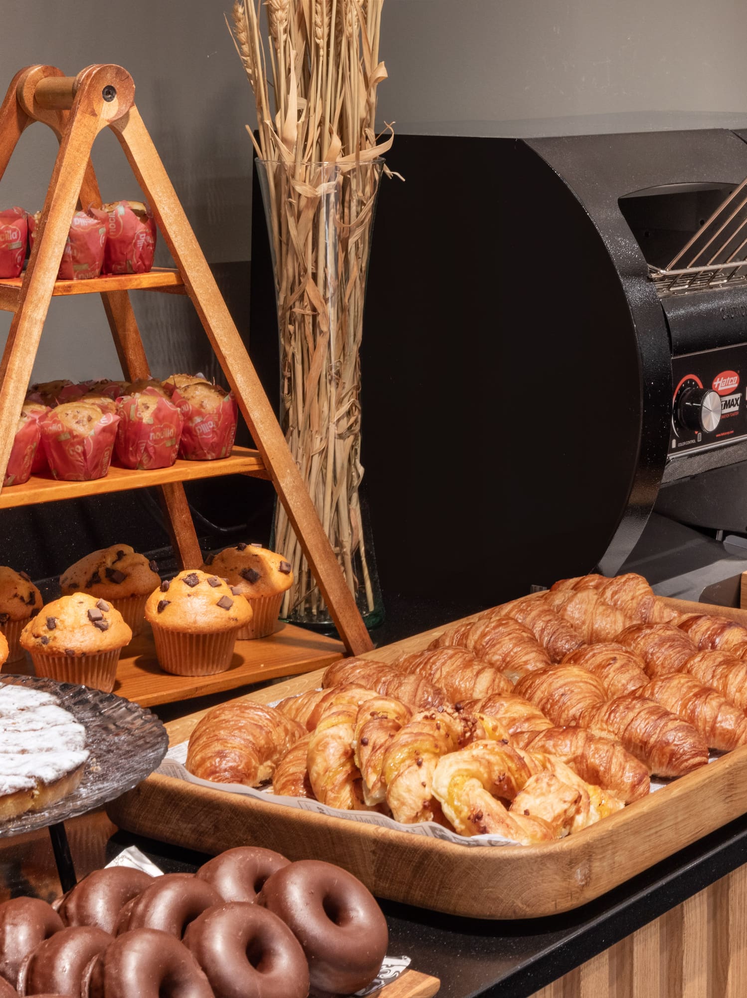 Buffet de desayuno con croissants, muffins, pastel, pan y tostadoras de autoservicio