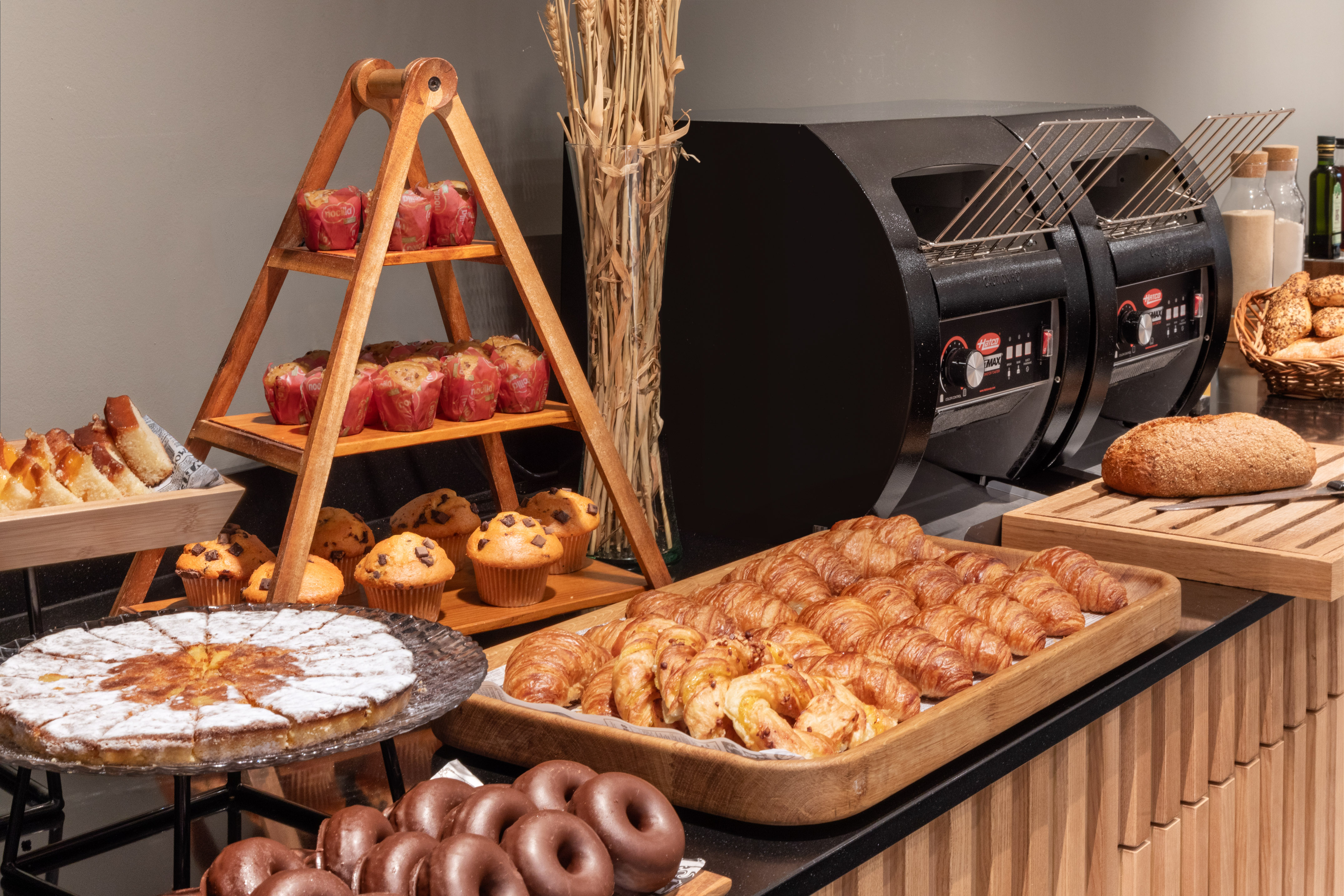 Buffet de desayuno con croissants, muffins, pastel, pan y tostadoras de autoservicio