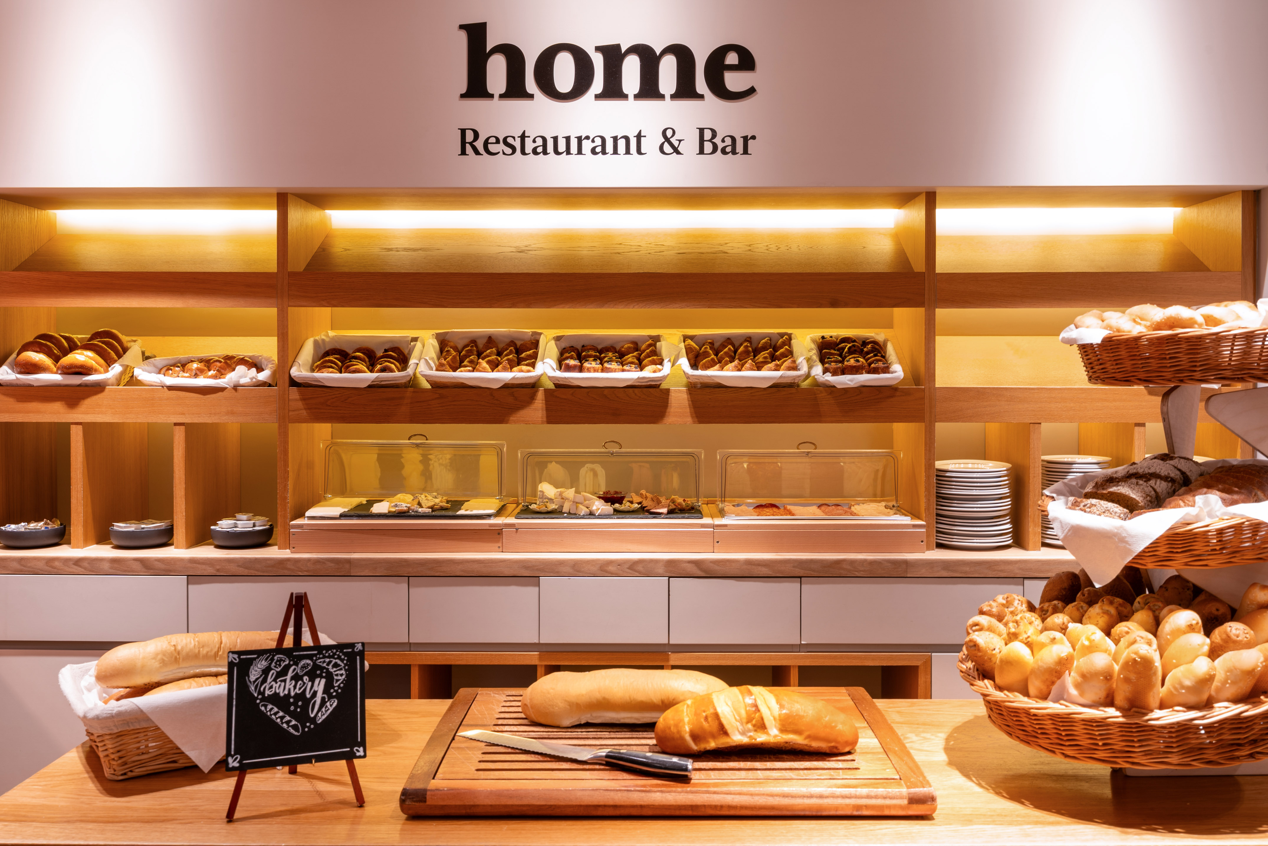 Home Restaurant breakfast buffet with fresh bread, pastries, and baked goods.