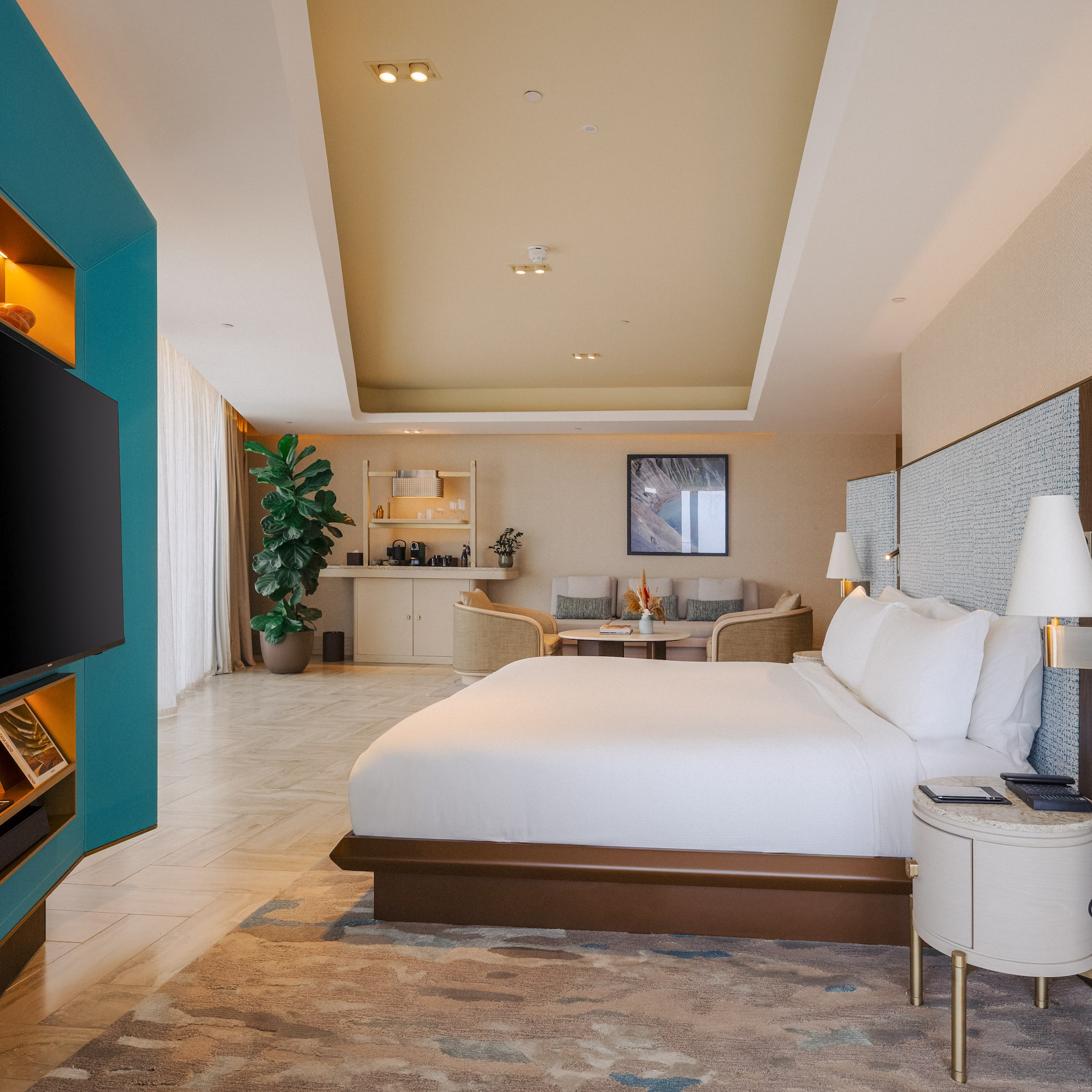 Luxury hotel suite bedroom with modern design, teal wall, king bed, and lounge.