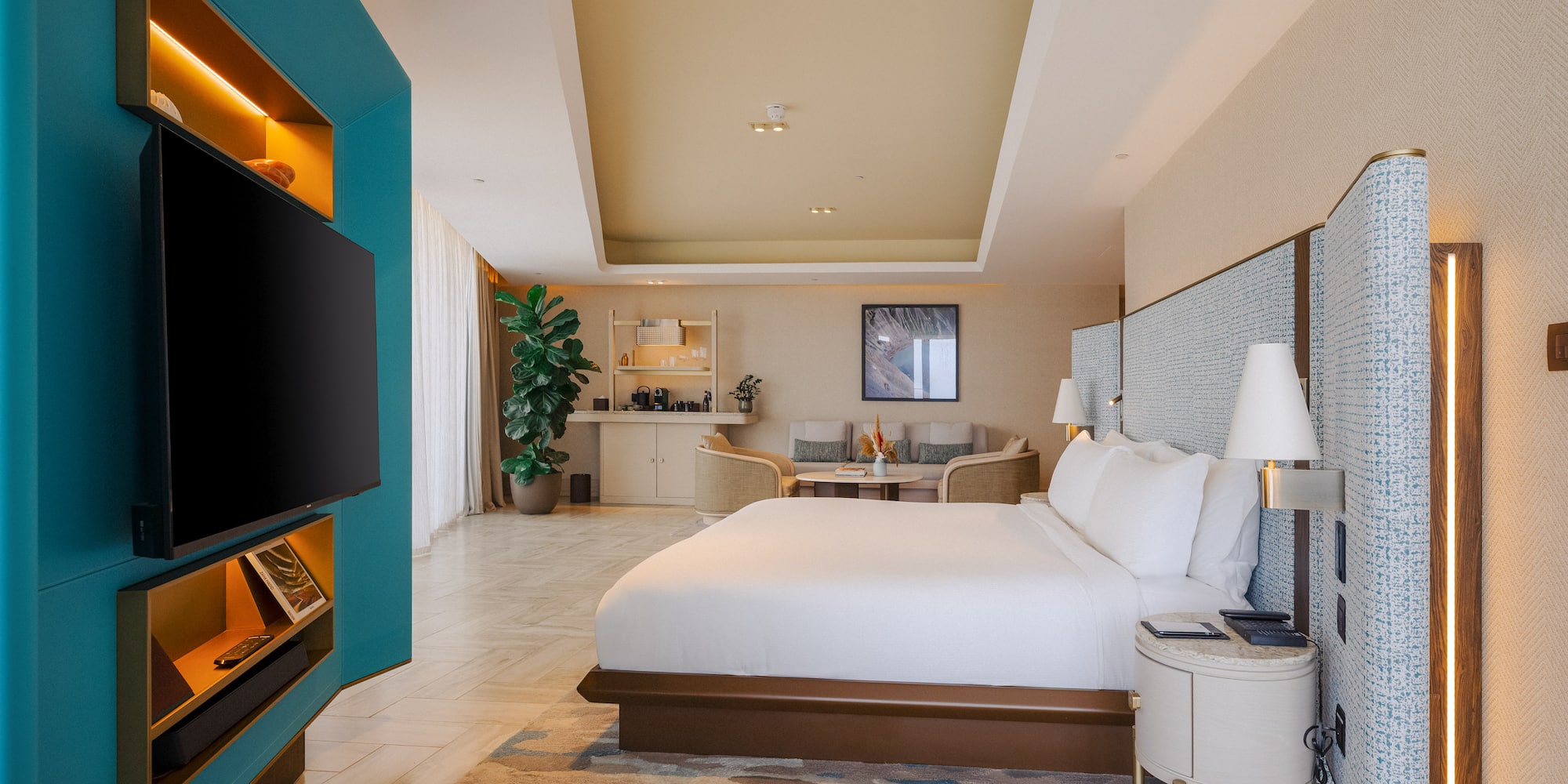Luxury hotel suite bedroom with modern design, teal wall, king bed, and lounge.