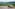 Pickup truck on scenic mountain road overlooking lush green valleys and hills.