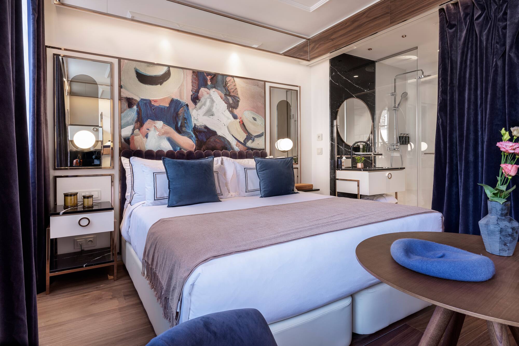 Modern hotel room with large bed, vibrant art, and elegant marble bathroom.