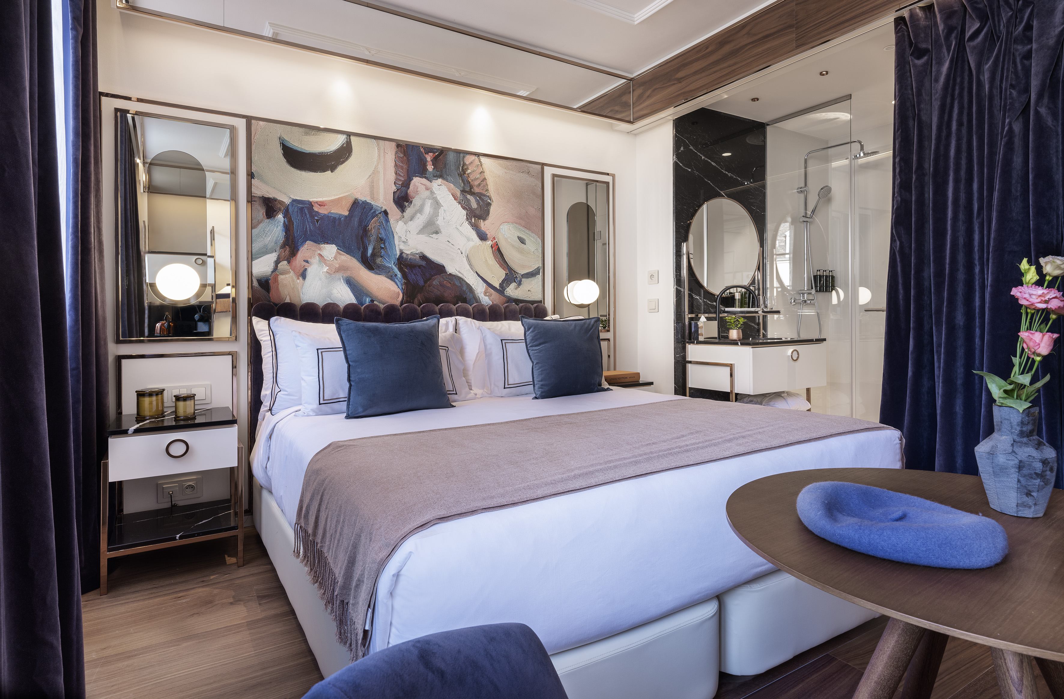Modern hotel room with large bed, vibrant art, and elegant marble bathroom.