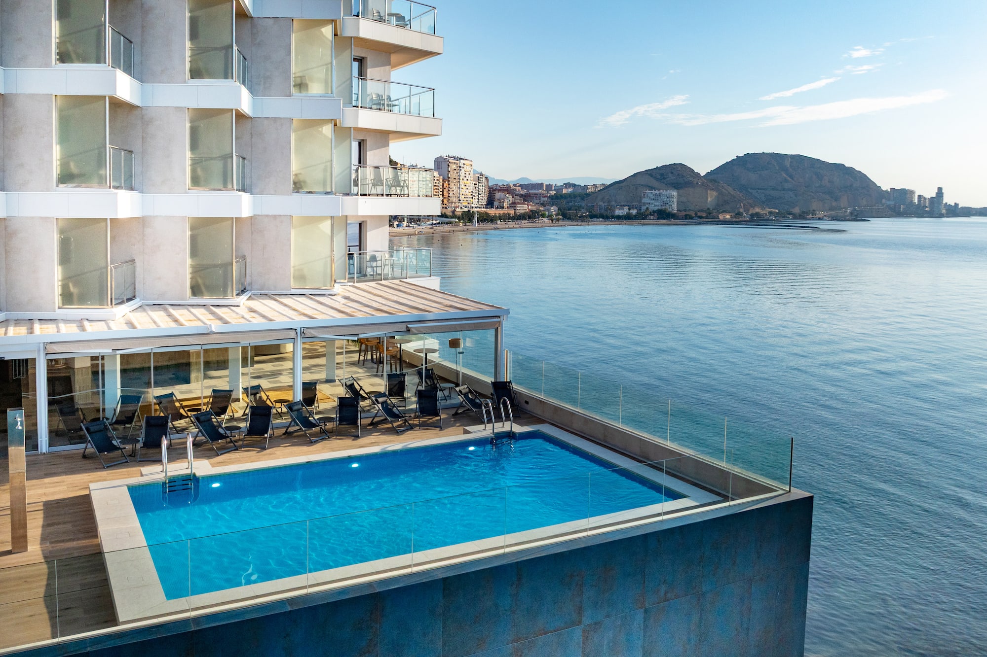 Luxury hotel rooftop pool overlooking the ocean, beach, and city skyline.