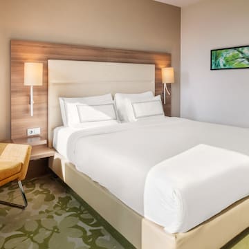 a bed with white sheets and a chair in a room