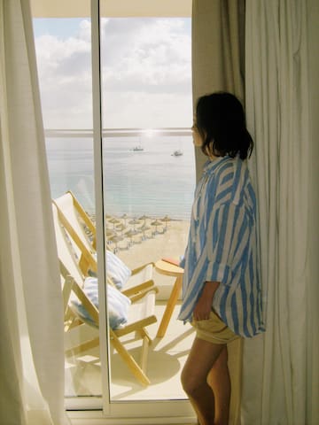 a woman standing in front of a window looking out to the ocean