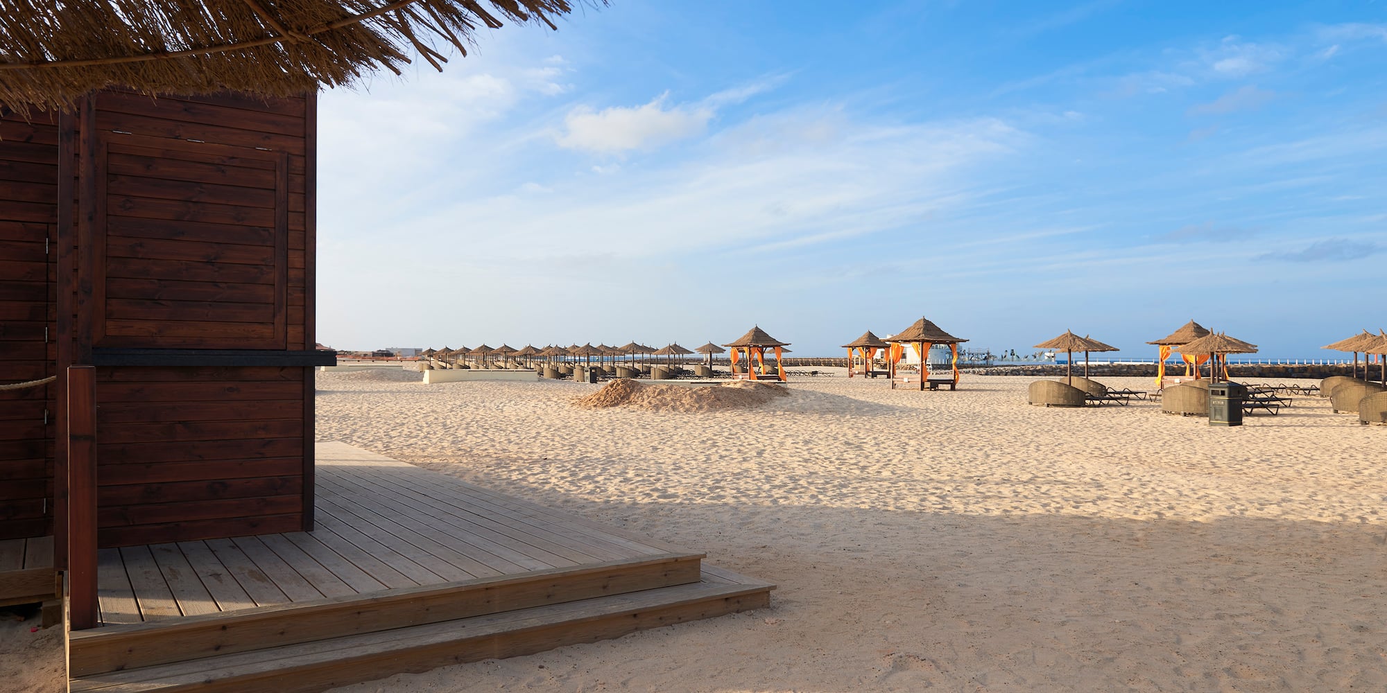 a beach with a hut and umbrellas