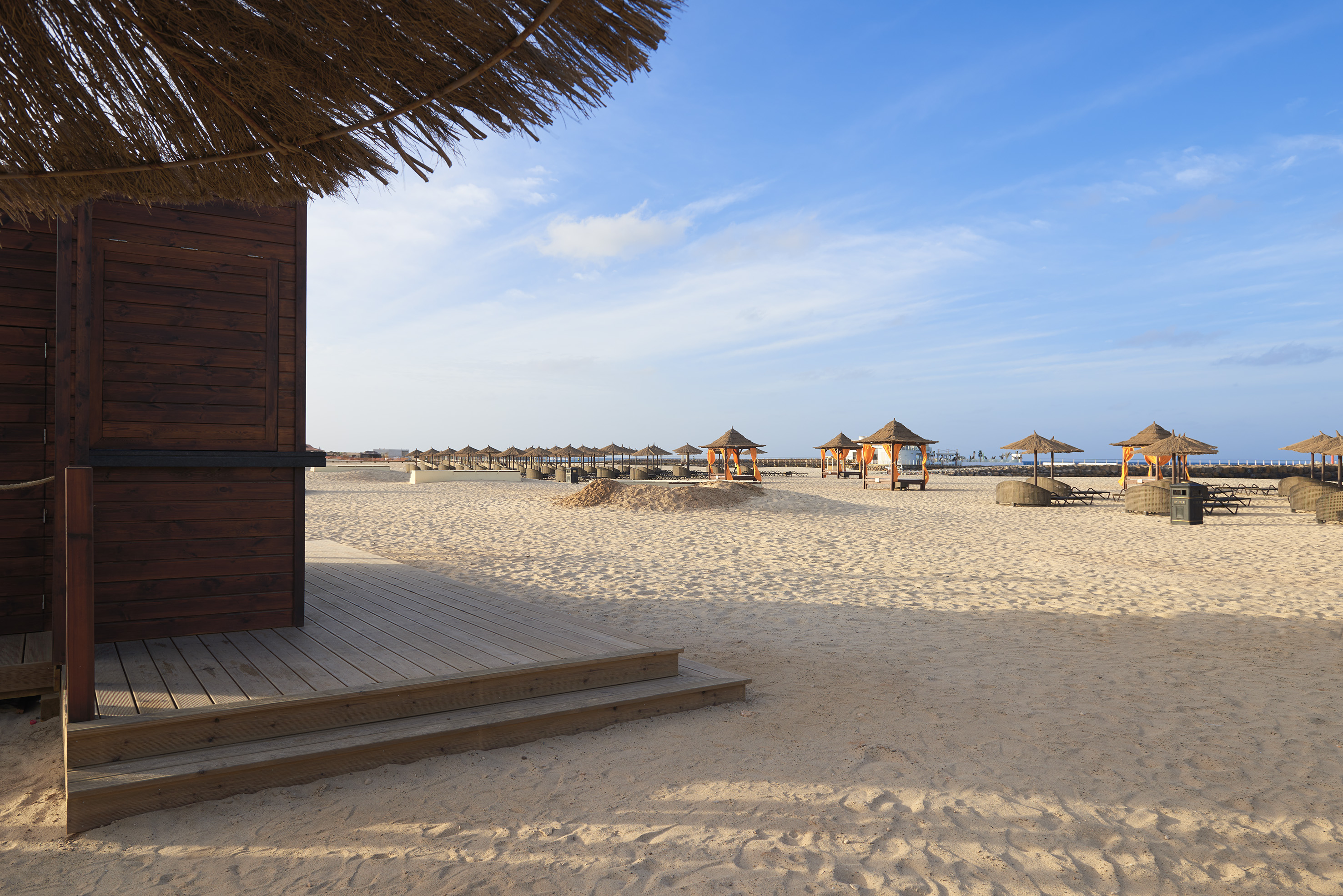 a beach with a hut and umbrellas