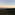 Sunrise over green valleys, distant Rock of Gibraltar, city, and wind turbines.