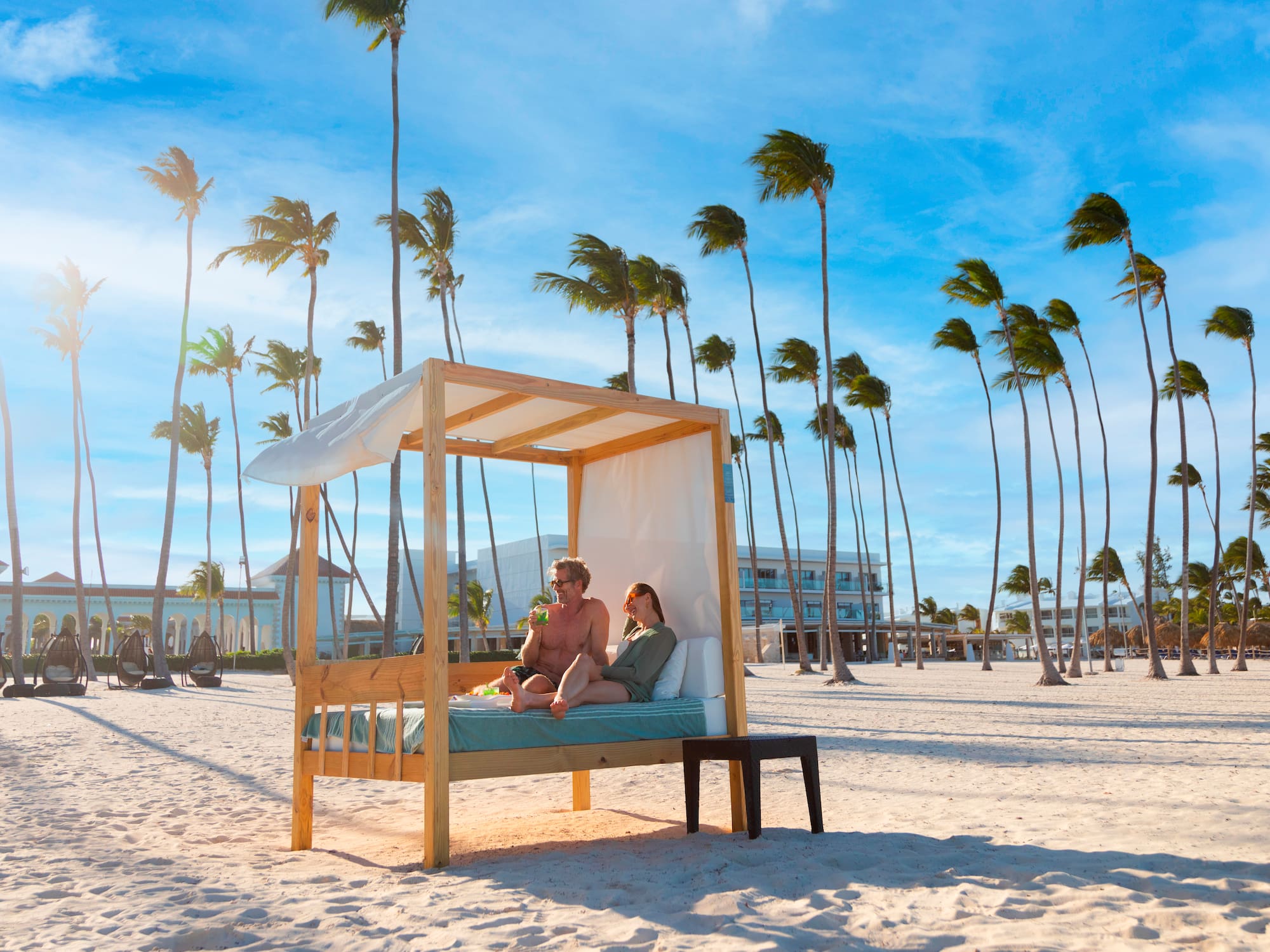 a couple sitting on a bed on a beach