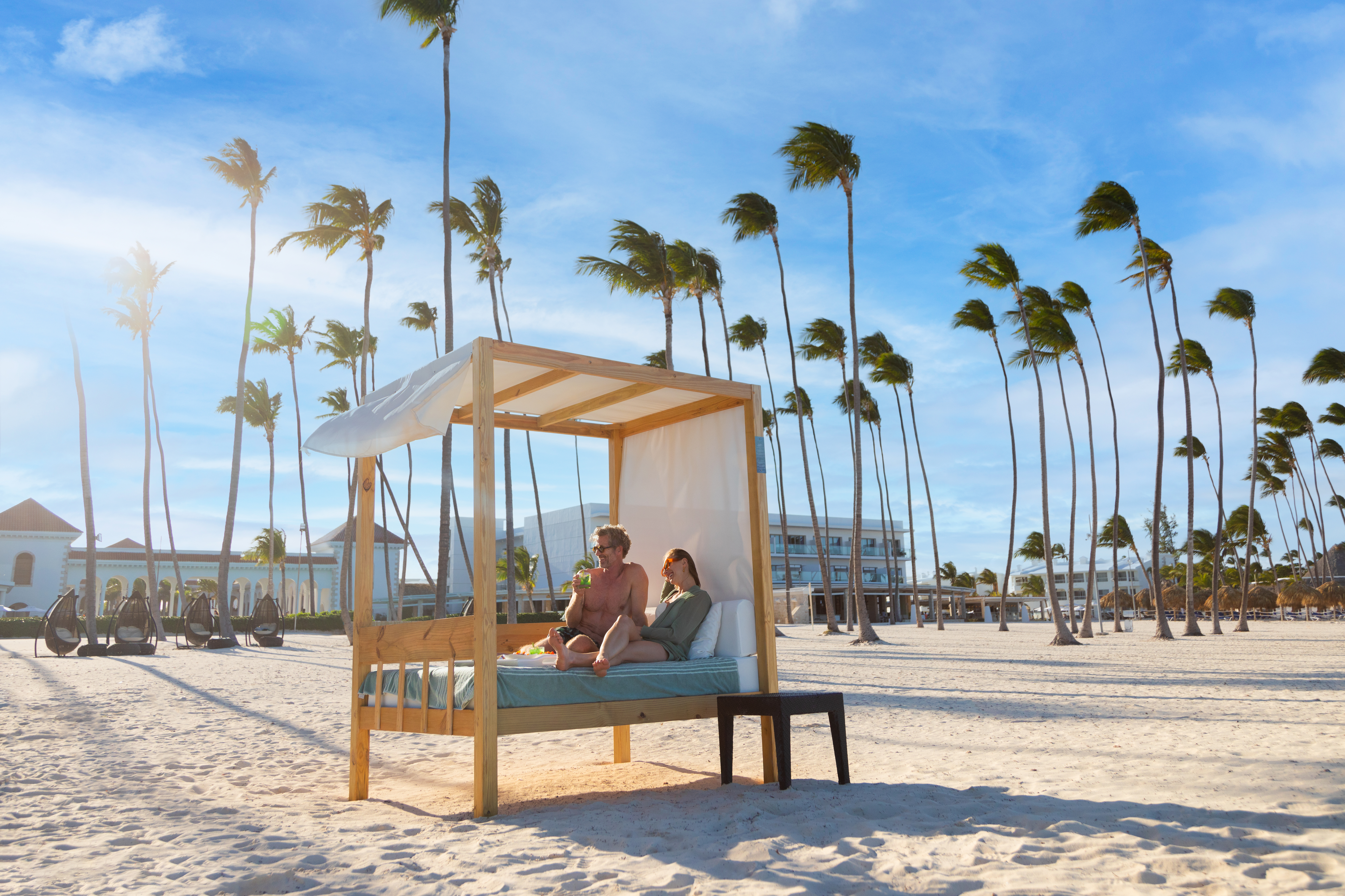 a couple sitting on a bed on a beach
