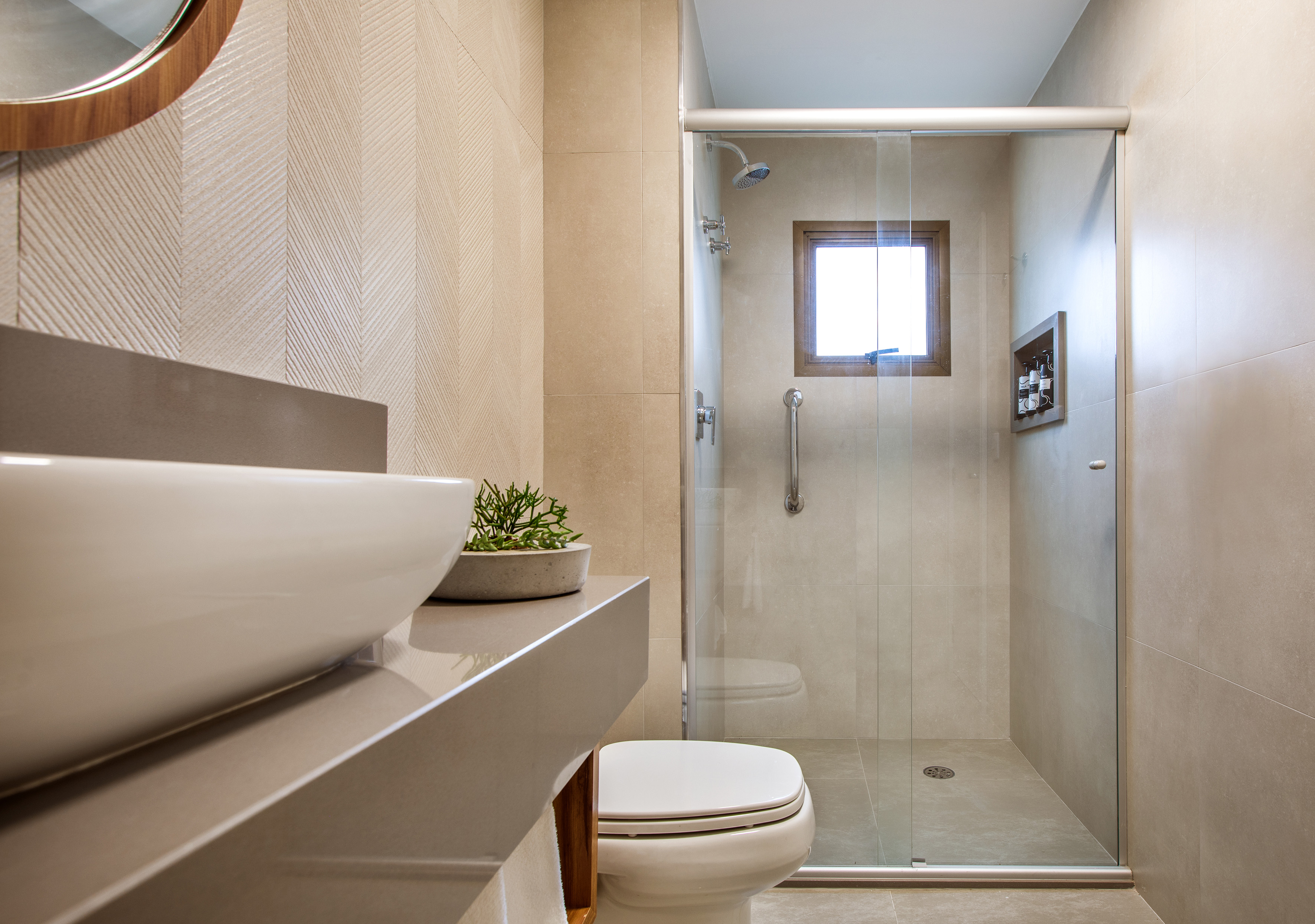 Modern beige bathroom with glass shower, vessel sink, and textured tiles.
