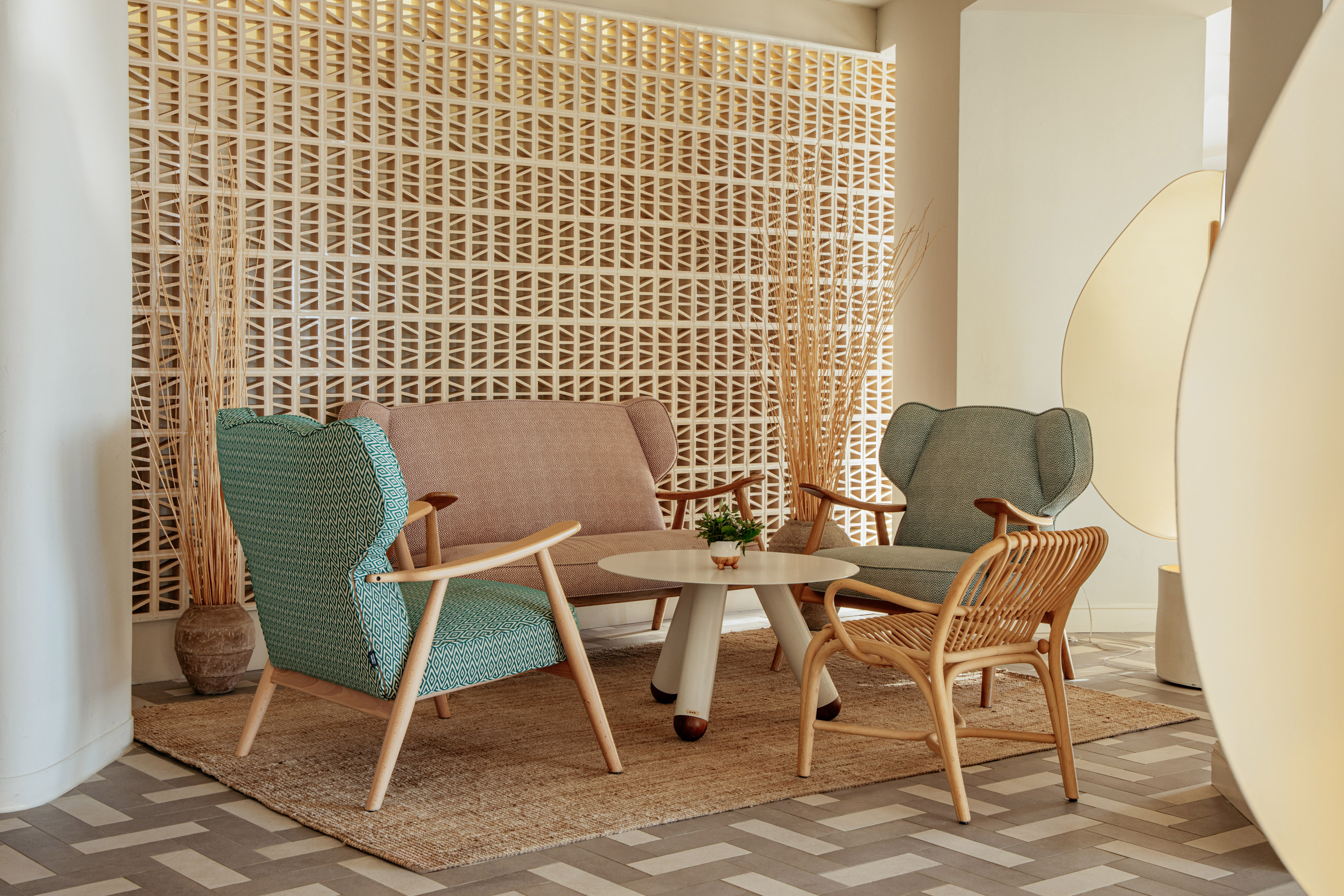 Modern lounge, geometric wall, sofa, accent chairs, coffee table, jute rug.