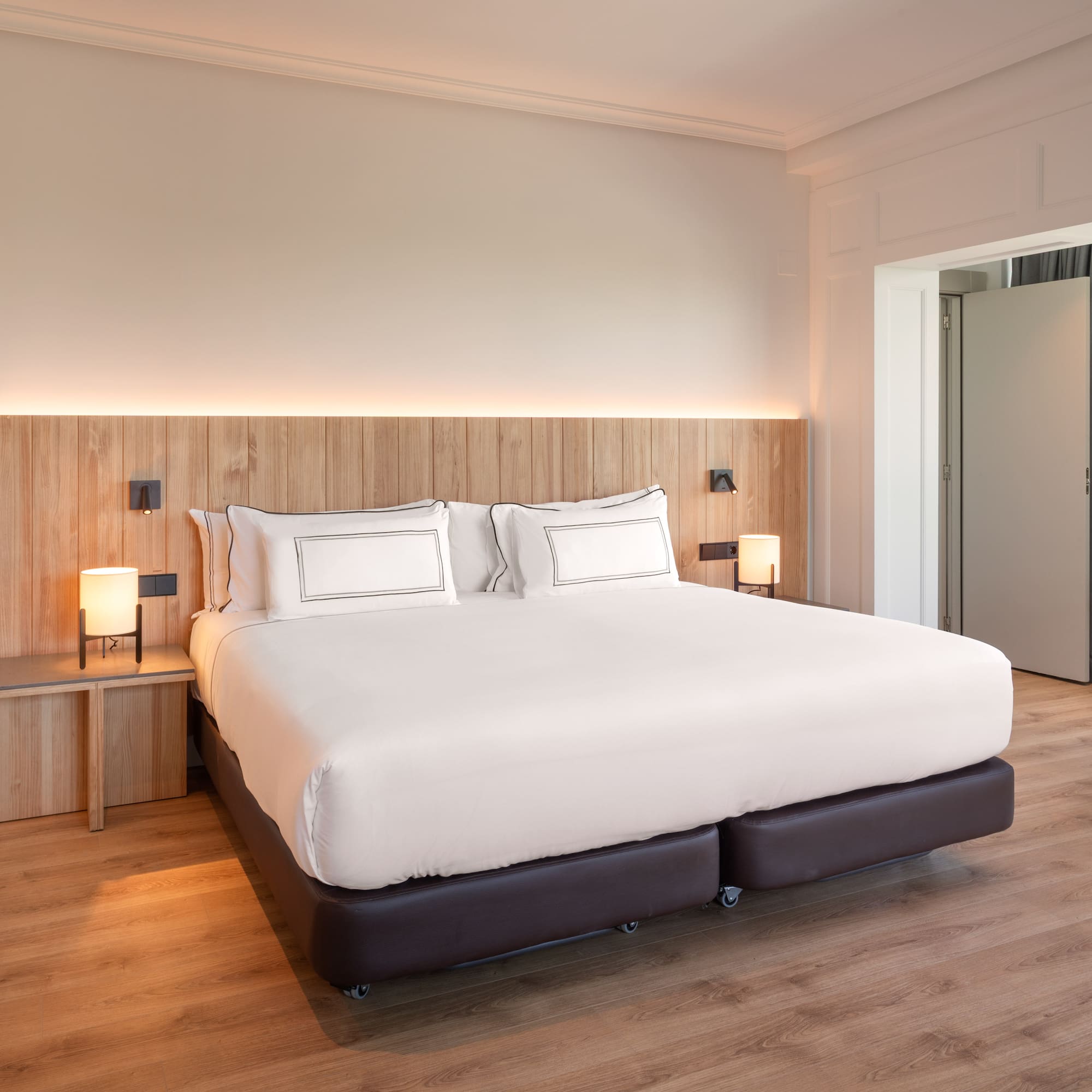 a bed with white sheets and a wood floor