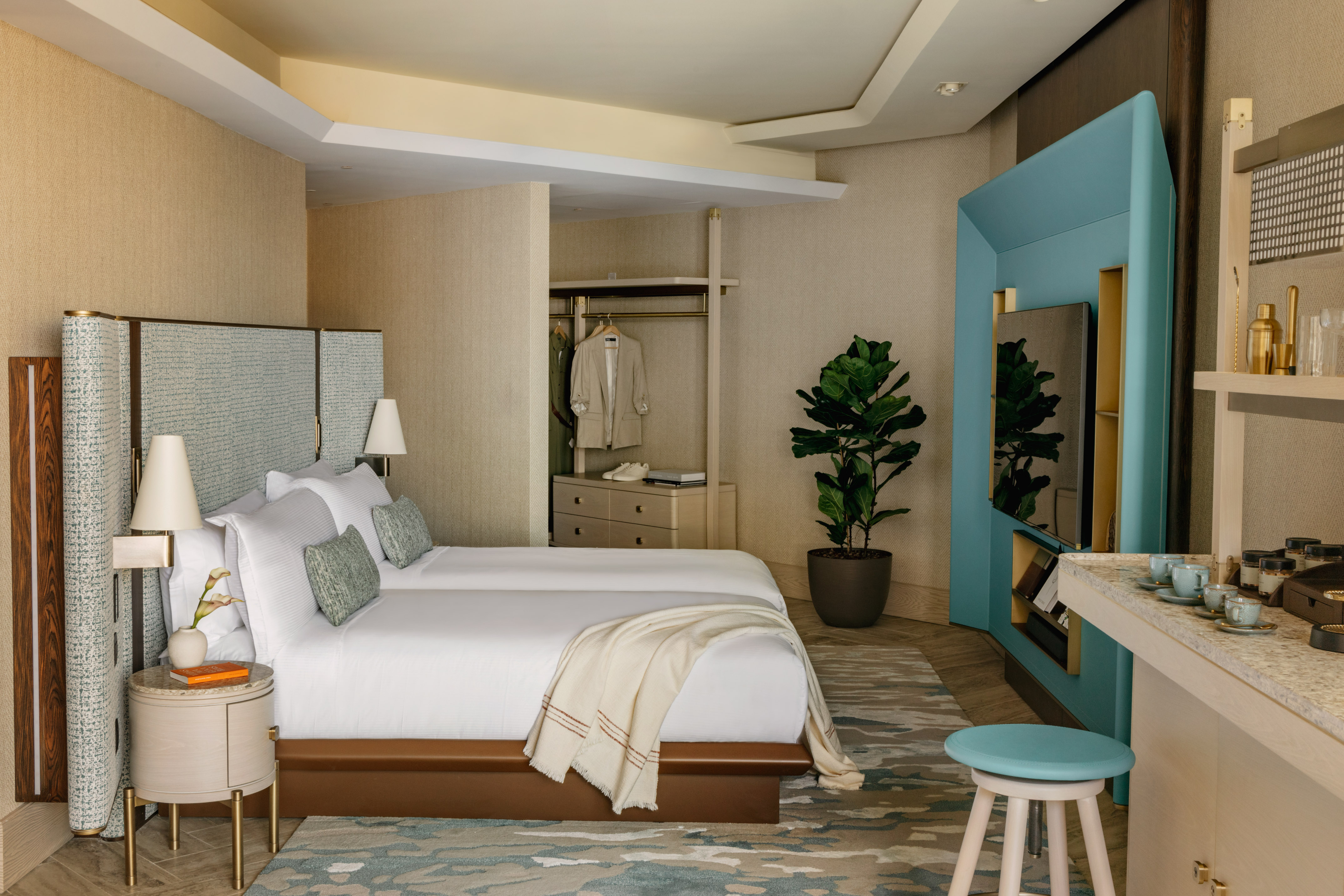 Modern luxury hotel room with two beds, blue accents, and contemporary design.
