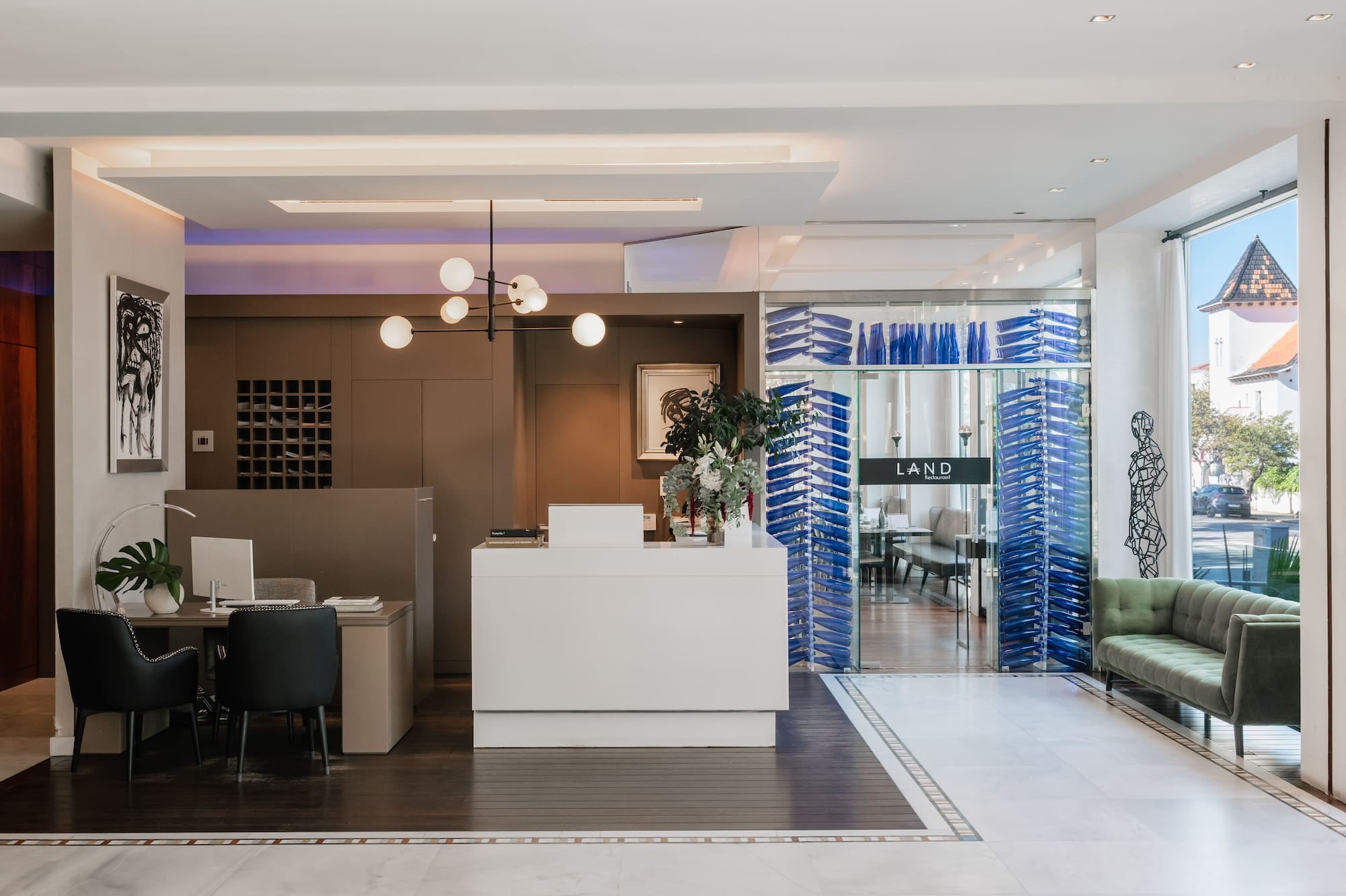 Modern hotel reception with white desk, green sofa, and blue glass partitions.