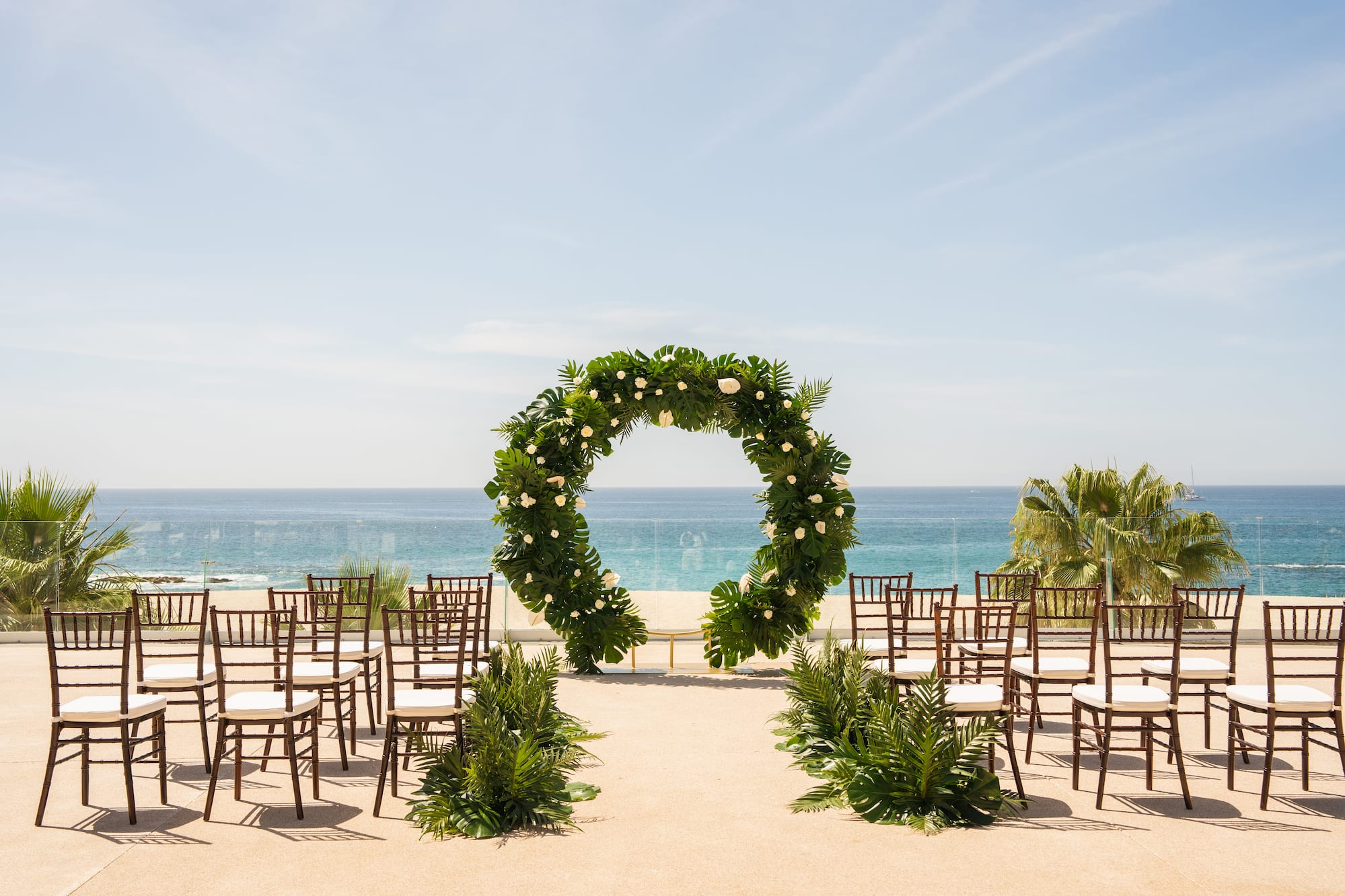a wedding ceremony set up with chairs and a wreath of flowers