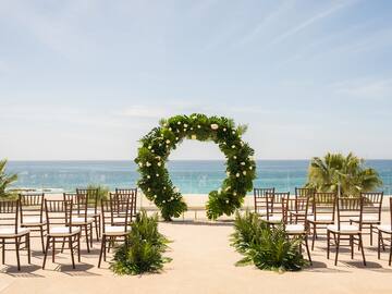 a wedding ceremony set up with chairs and a wreath of flowers