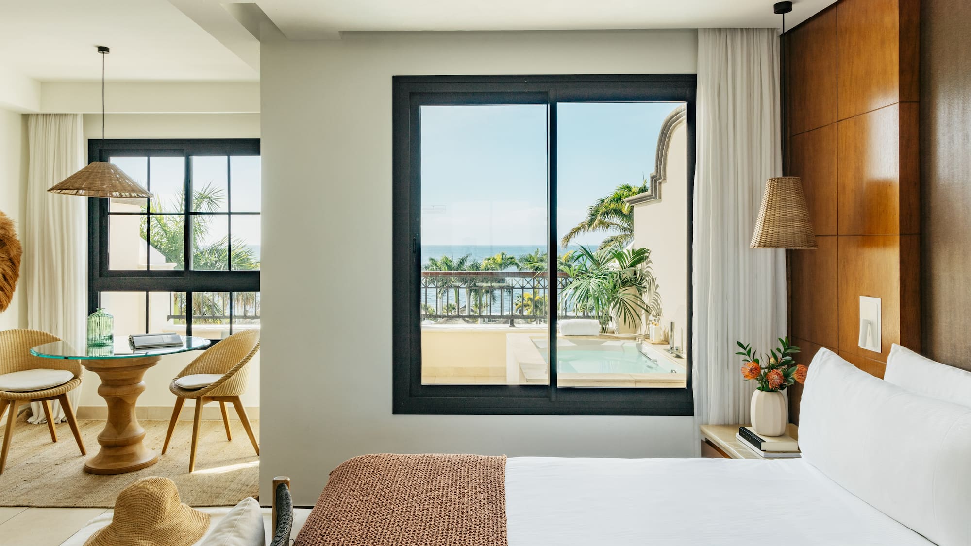 a bedroom with a view of the ocean and a glass door
