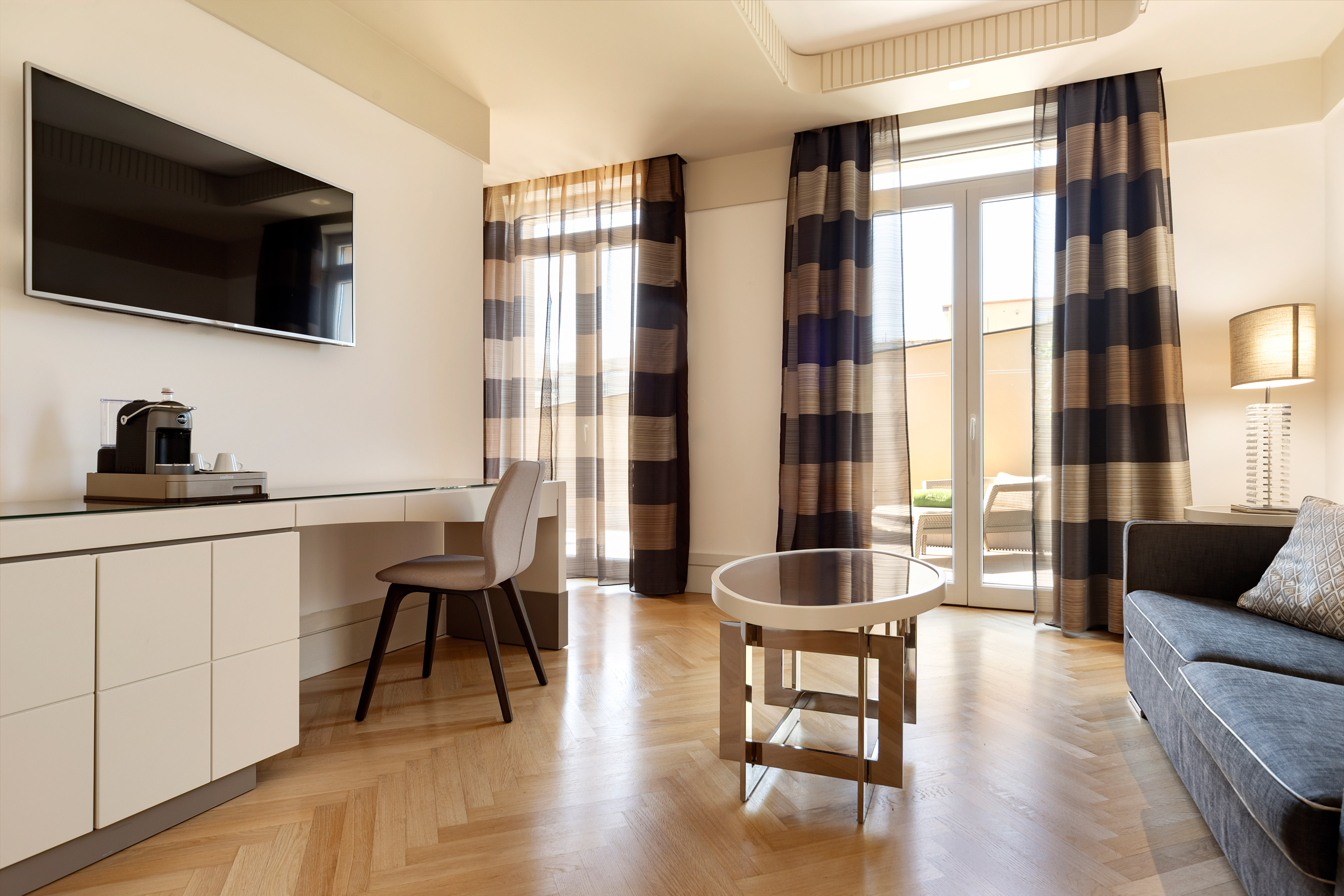 Hotel suite living area with TV, coffee maker, sofa, and herringbone wood floor. - Grand Suite met Terras - Meliá Genova, Genua